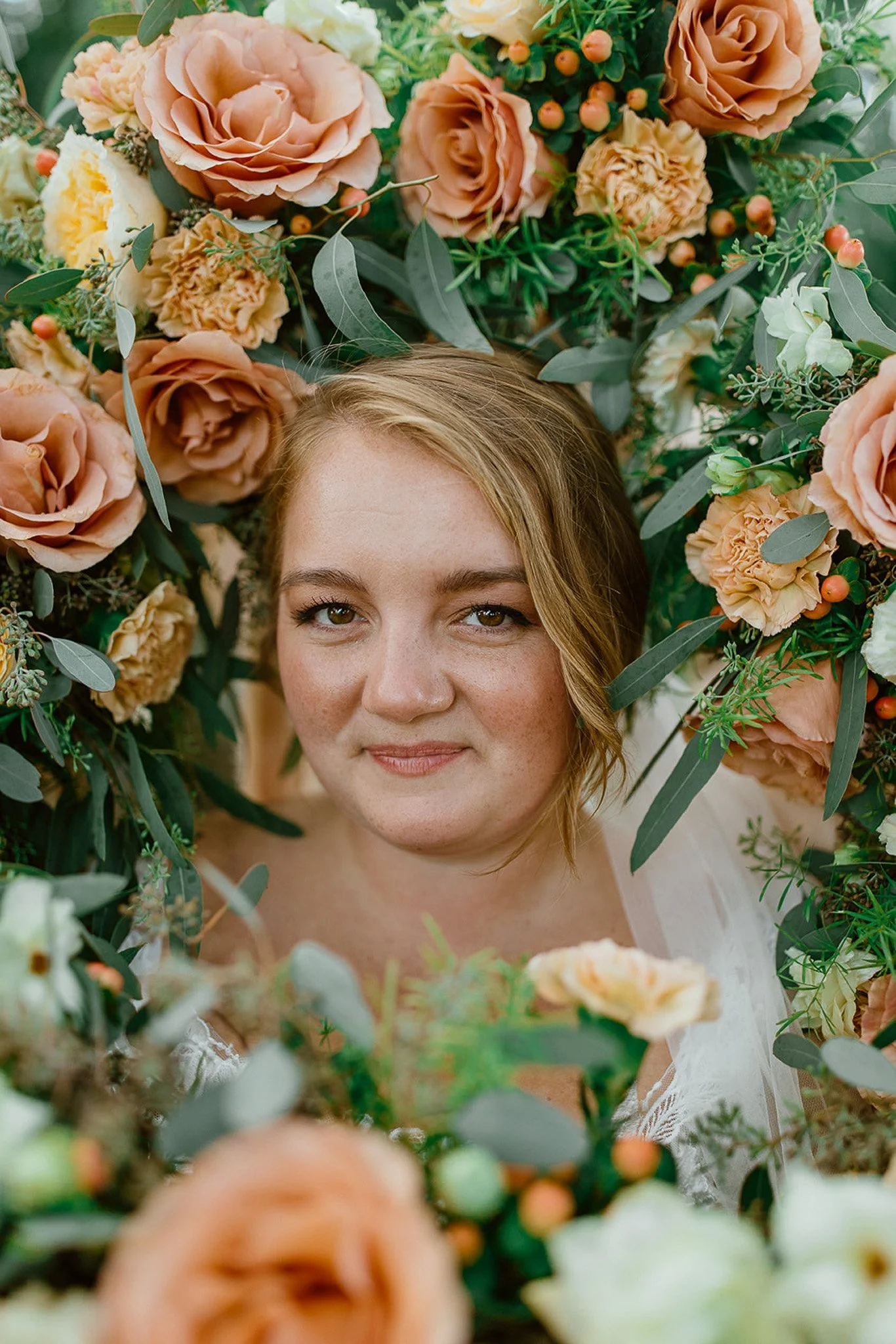 Bride portrait framed by colourful wedding flowers