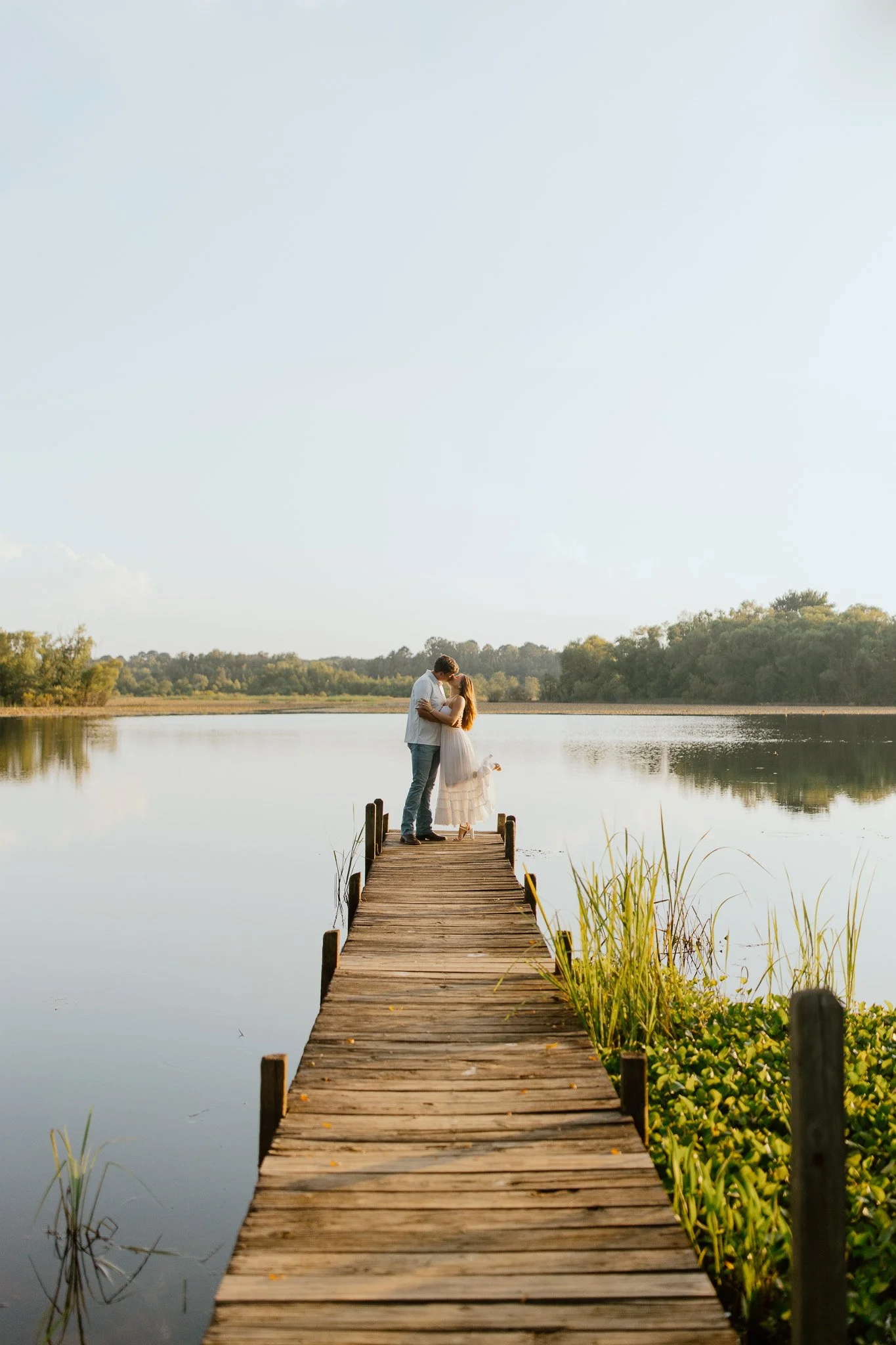 Couple embracing at the end of a wooden dock overlooking a lake