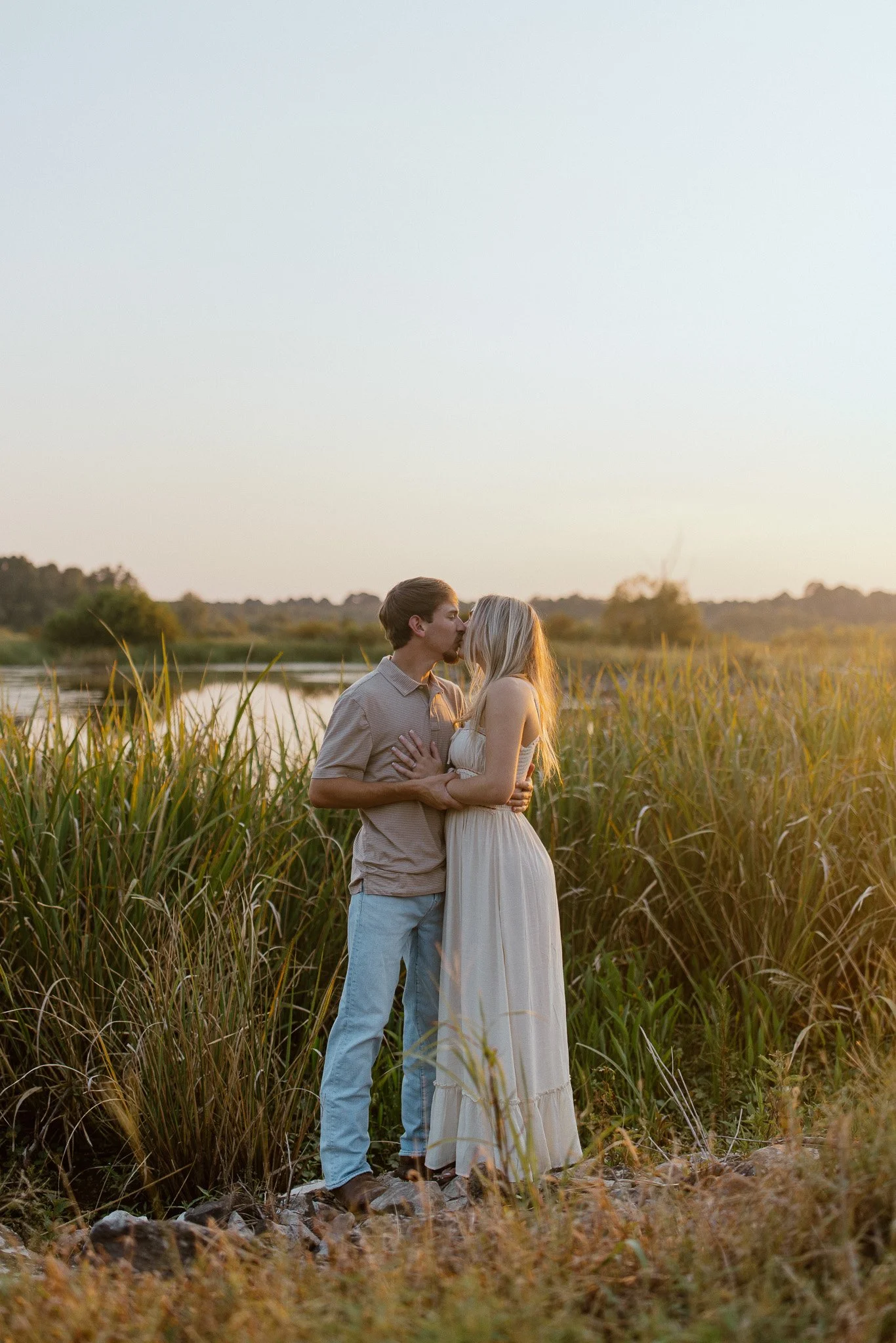 Couple embracing beside tall grass during a sunset photography session