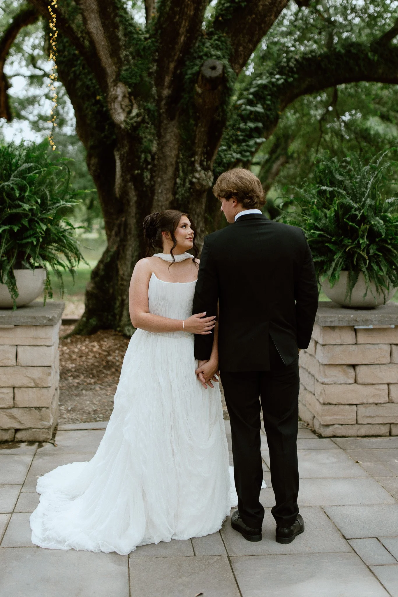 Bride and groom holding hands beneath a large tree