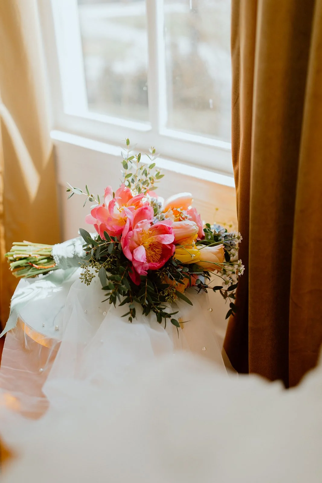 Colourful bridal bouquet resting beside a sunlit window