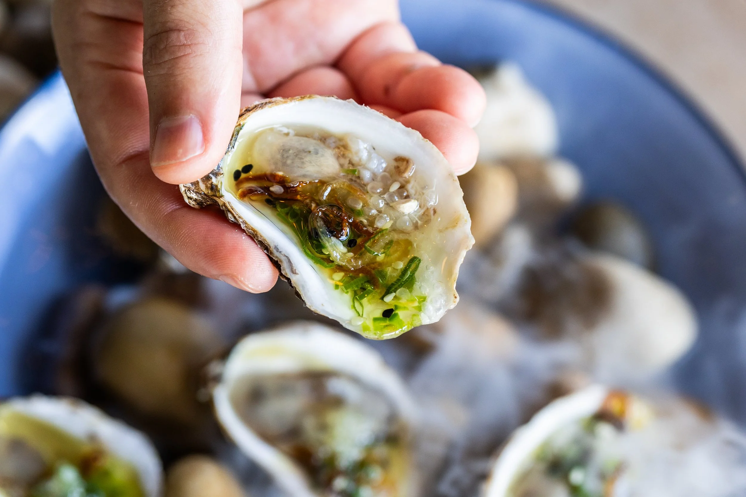 East Coast Oyster dressed with a green salsa macha and fingerlime, topped eith crispy onions. Photograph by Richard Casteel of Austin Texas for Daffodil Culinary and Catering