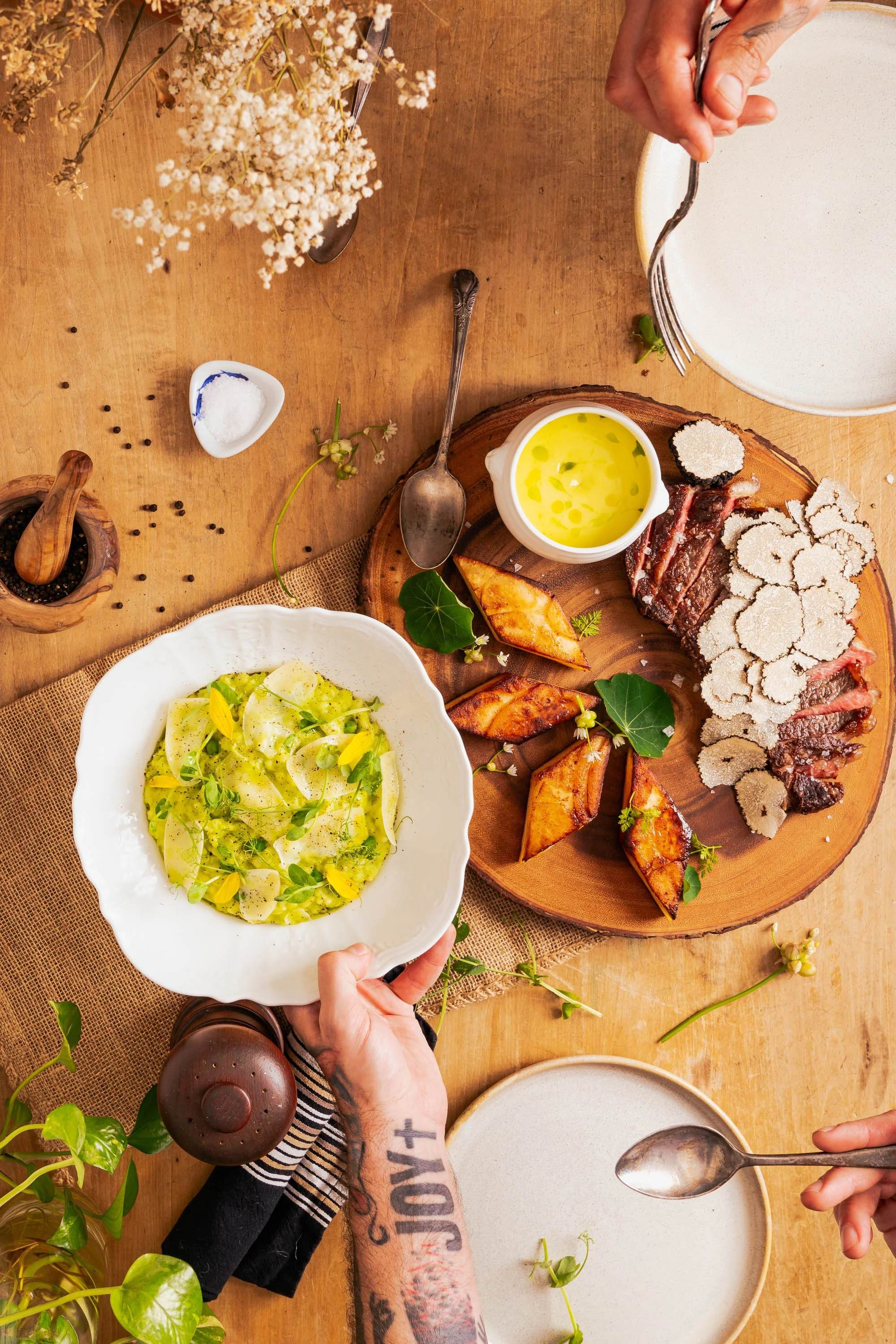 Texas Wagyu Ribeye with Potato Pave and shaved truffle. Served alongside a creamy Carolina Gold Rice with spring peas and pea shoots, shaved cheese on top. Served family style with leek hollandaise sauce on the side. Photograph by Cameron Kisel