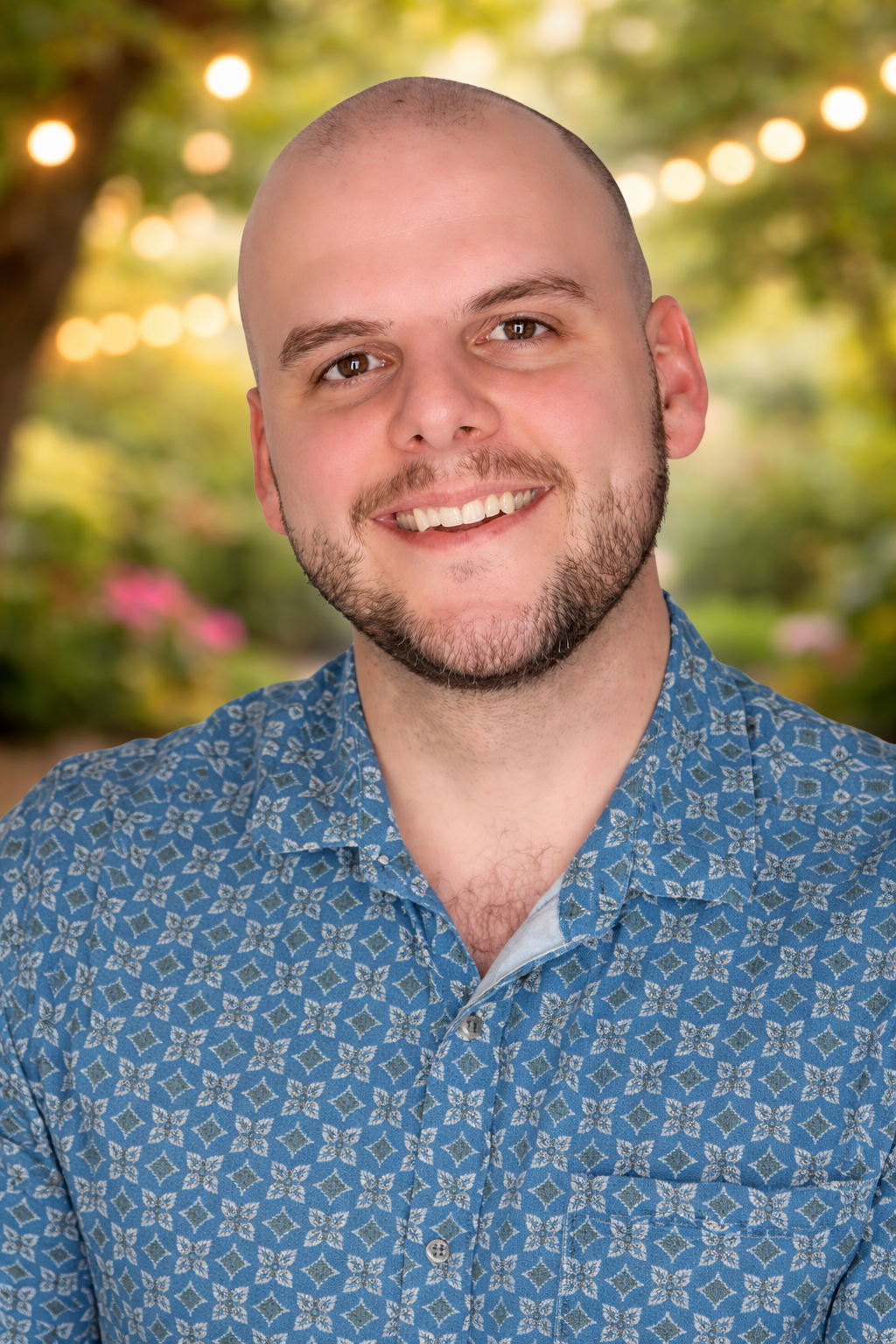 Guy smiling warmly in a grey collared shirt.