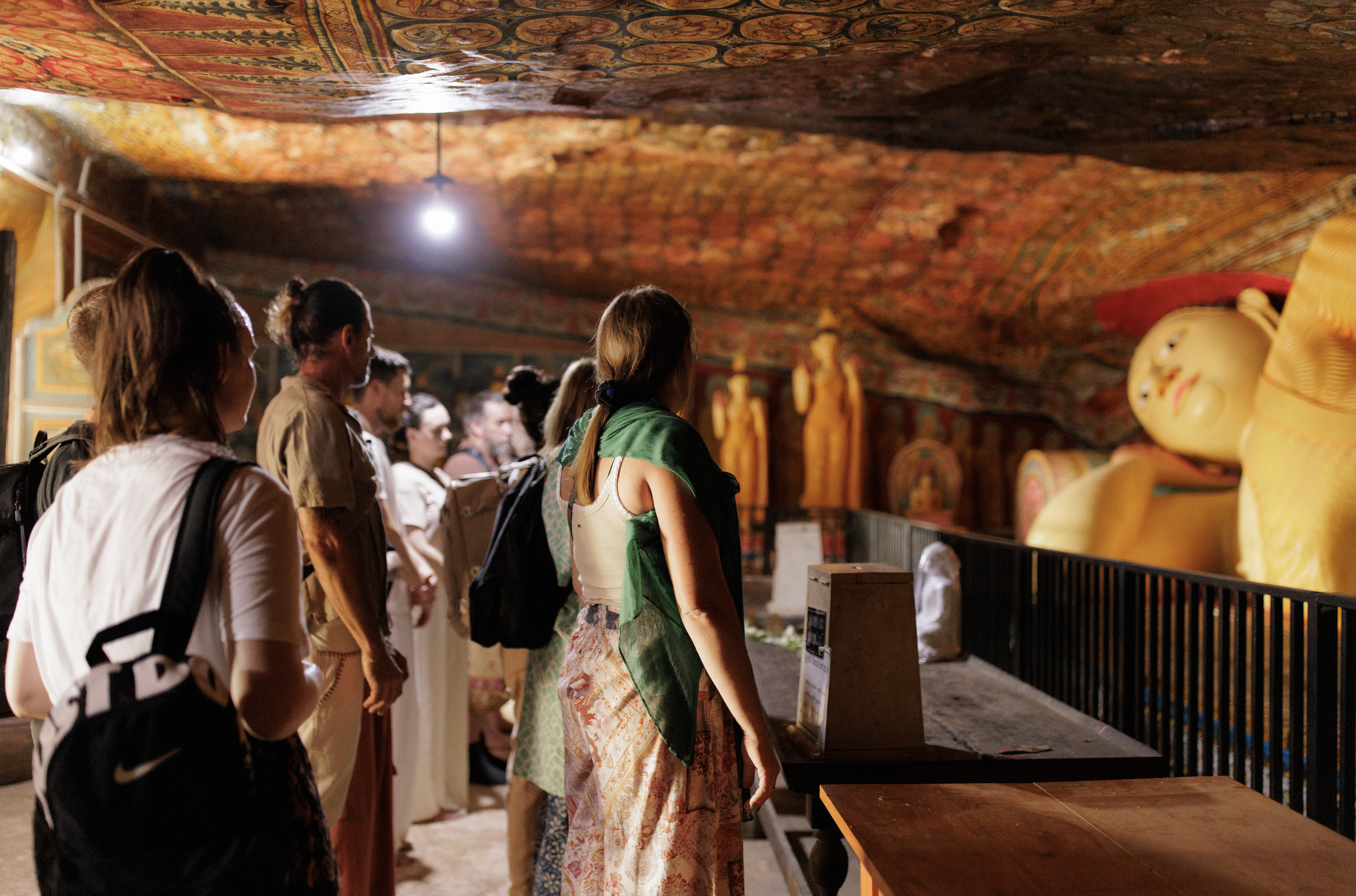 Group of people inside a temple with reclining Buddha statues.