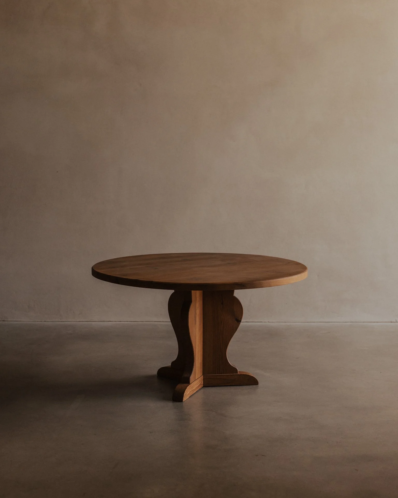 Vintage Swedish stained pine coffee table designed by Axel Einar Hjorth for Nordiska Kompaniet, circa 1930s, with a sculptural three-part base and round tabletop