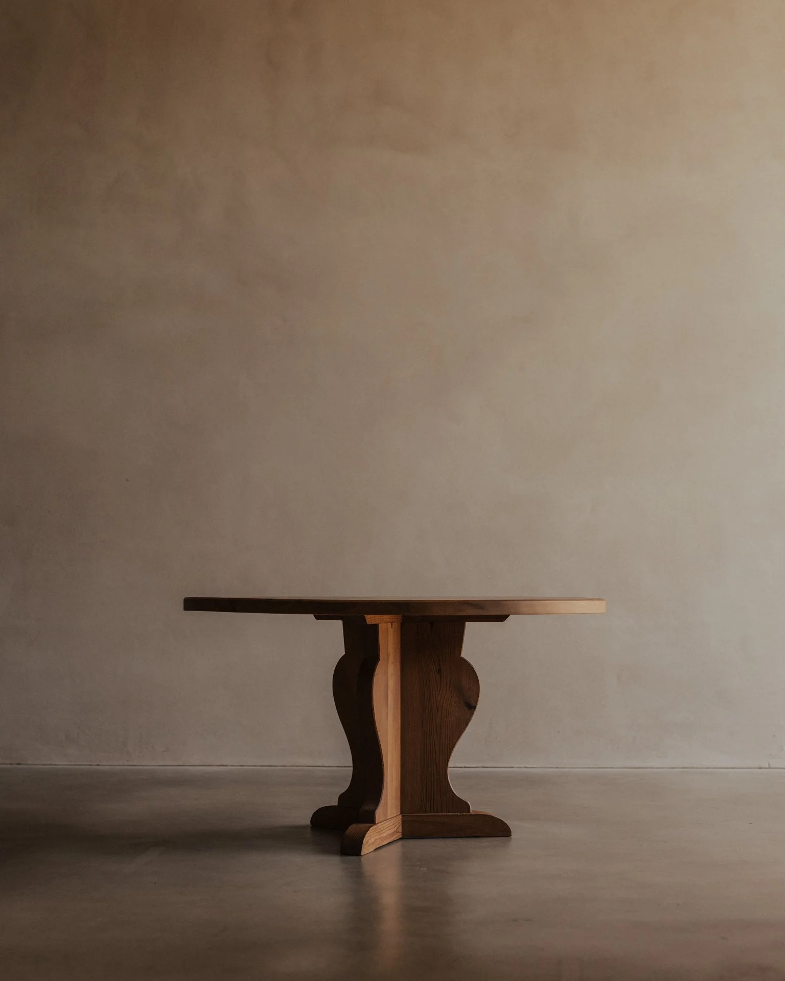 Vintage Swedish stained pine coffee table designed by Axel Einar Hjorth for Nordiska Kompaniet, circa 1930s, with a sculptural three-part base and round tabletop