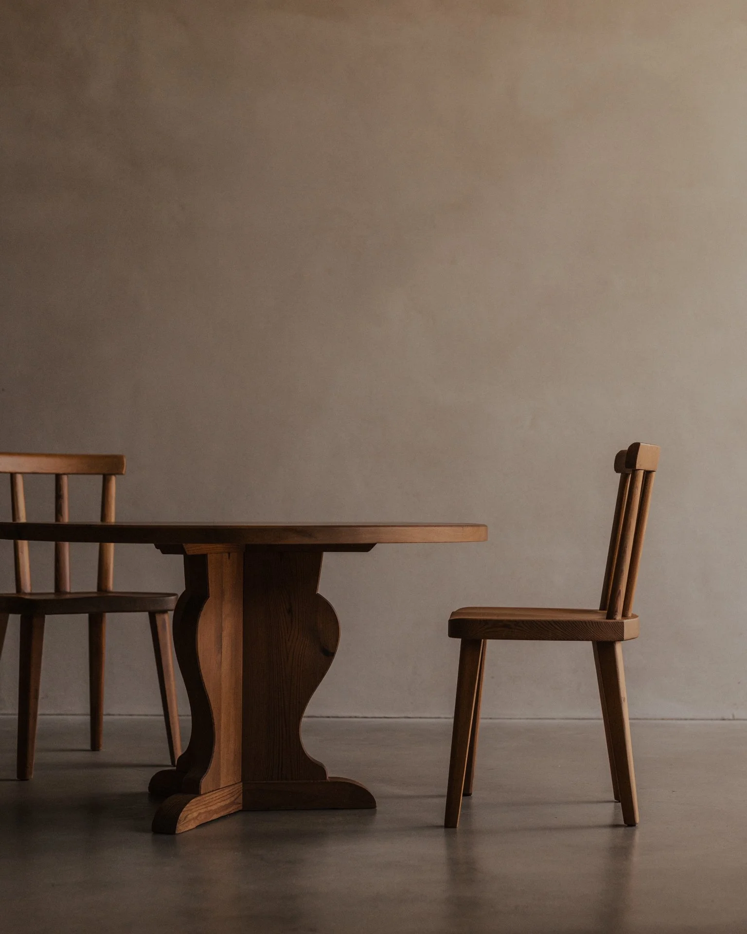 Vintage Swedish stained pine coffee table designed by Axel Einar Hjorth for Nordiska Kompaniet, circa 1930s, with a sculptural three-part base and round tabletop