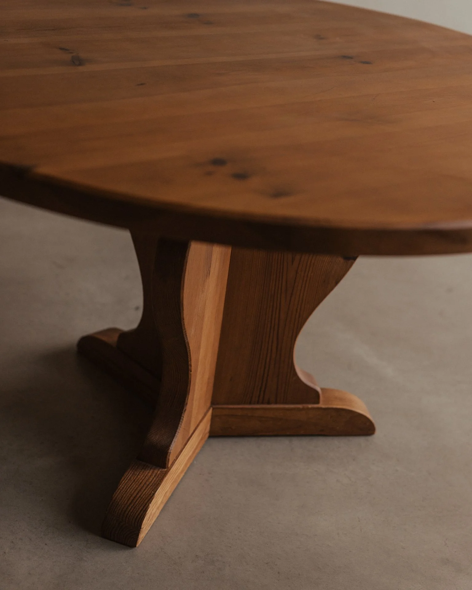Vintage Swedish stained pine coffee table designed by Axel Einar Hjorth for Nordiska Kompaniet, circa 1930s, with a sculptural three-part base and round tabletop