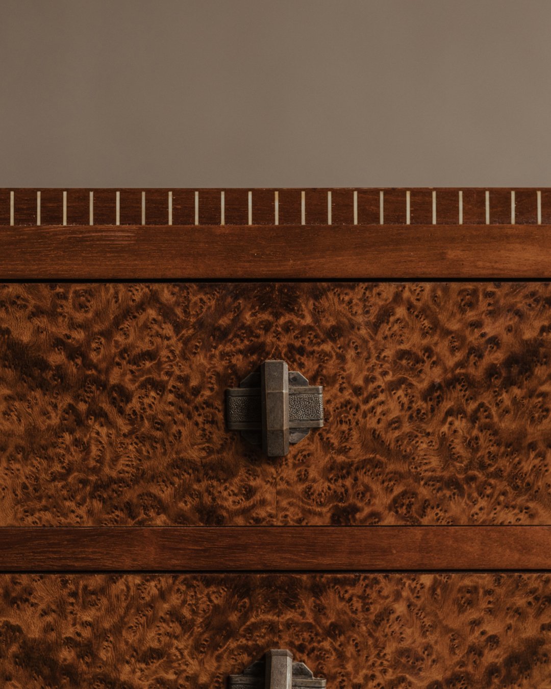 Mid-20th-century Art Deco–inspired burl wood chest of drawers with four stacked drawers, geometric metal handles, and a stepped base