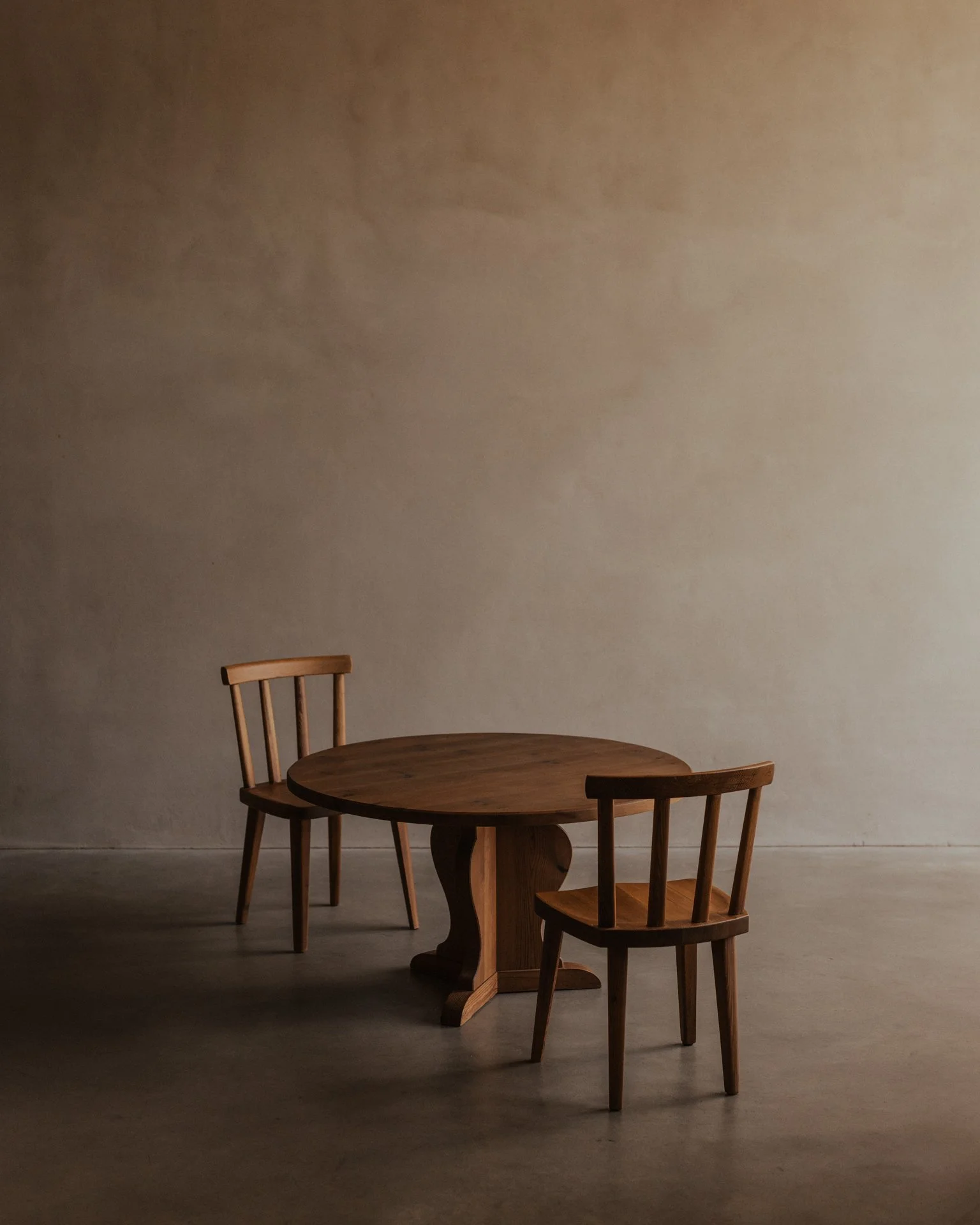 Vintage Swedish stained pine coffee table designed by Axel Einar Hjorth for Nordiska Kompaniet, circa 1930s, with a sculptural three-part base and round tabletop