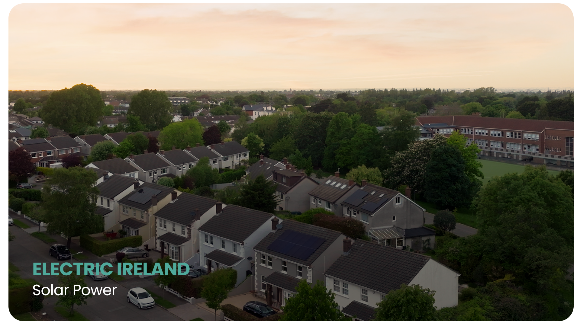 A neighborhood with houses and trees under a cloudy sky, with a school building in the background, overlaid with the text 'Electric Ireland' and 'Solar Power'.