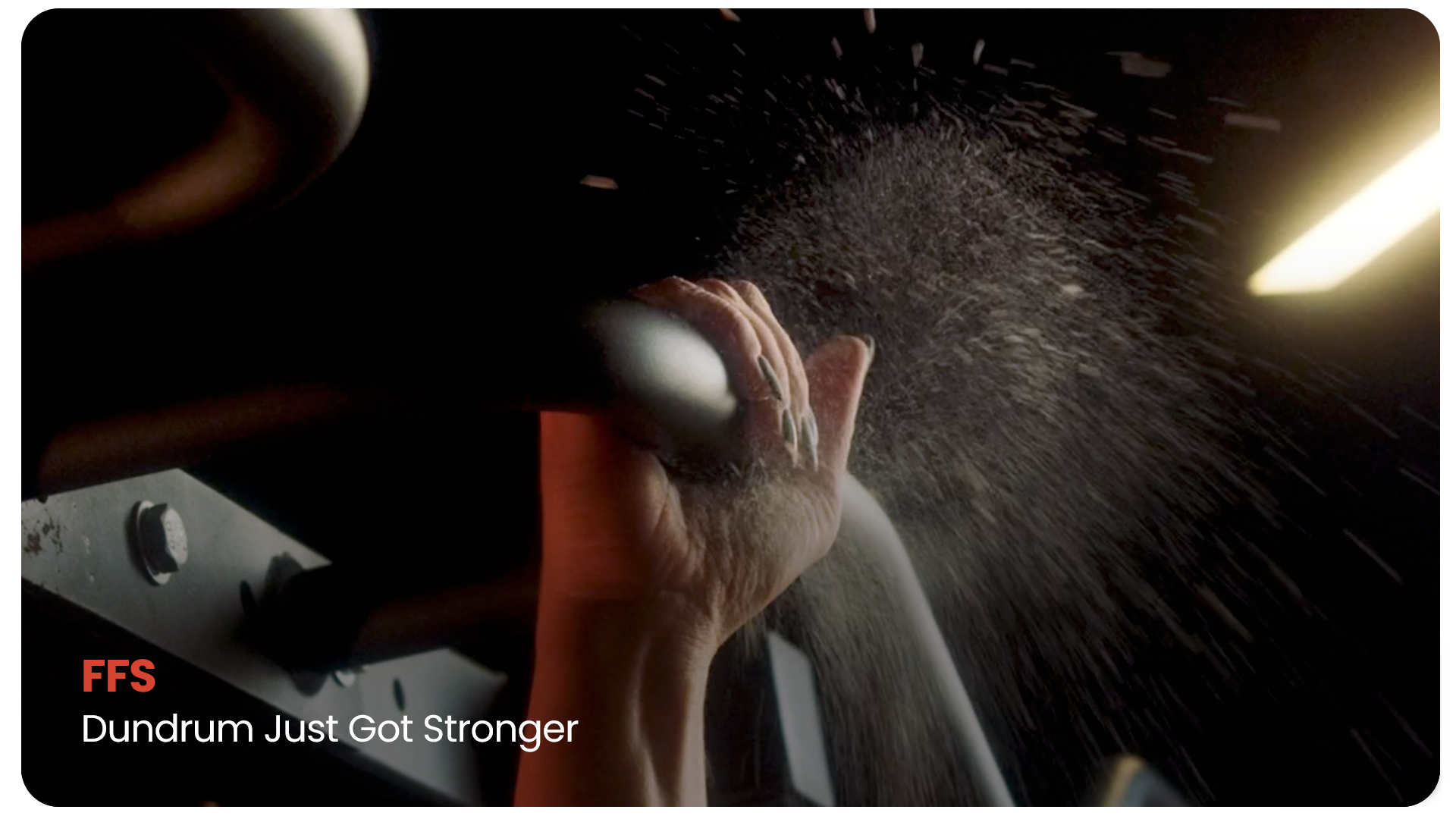 Close-up of a hand gripping a dough hook on a stand mixer, flour dust flying in the air in a bakery or kitchen setting.