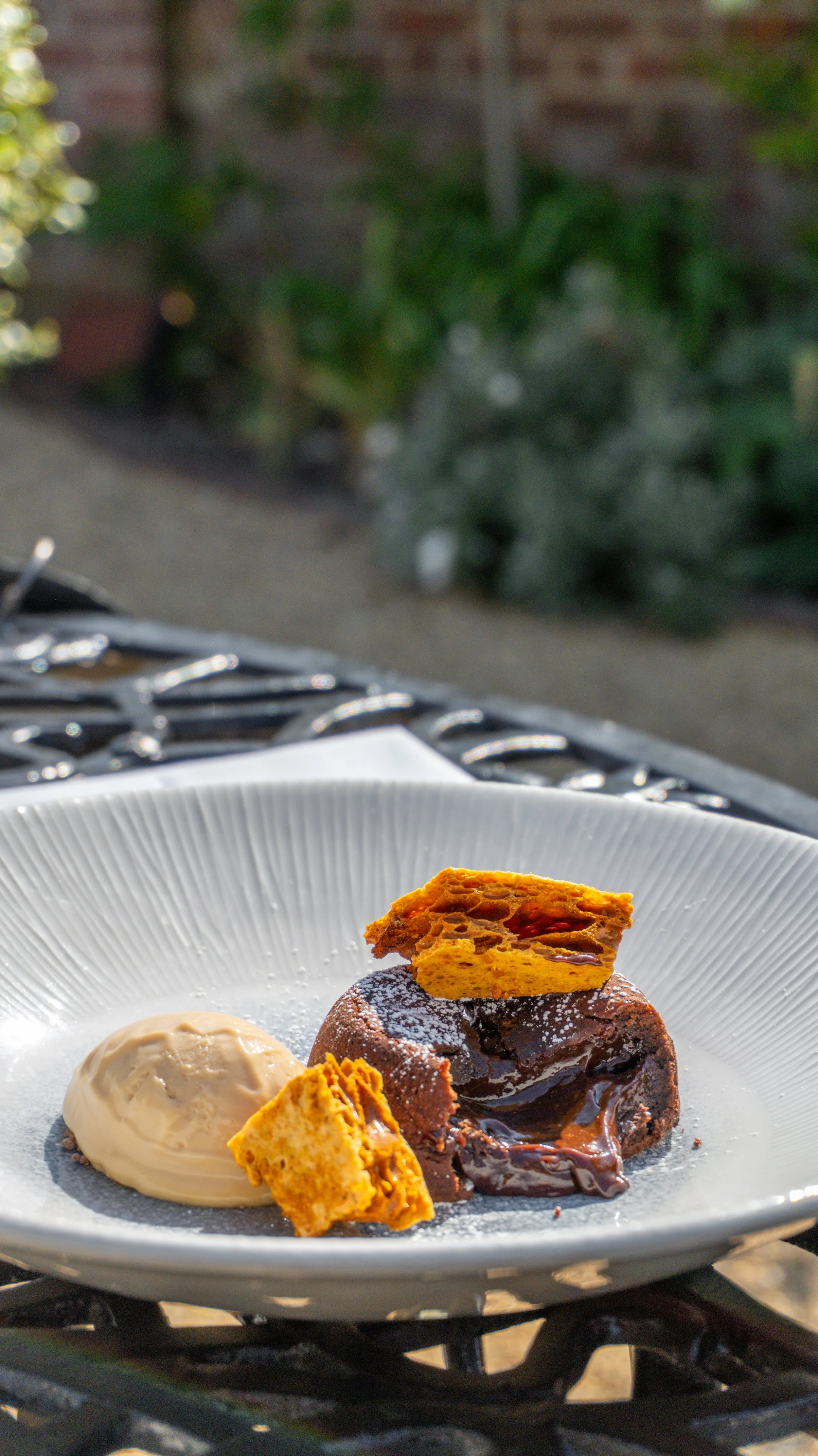Dessert plate with chocolate cake and ice cream, topped with a piece of honeycomb toffee, outdoors on a table at Stanwell House