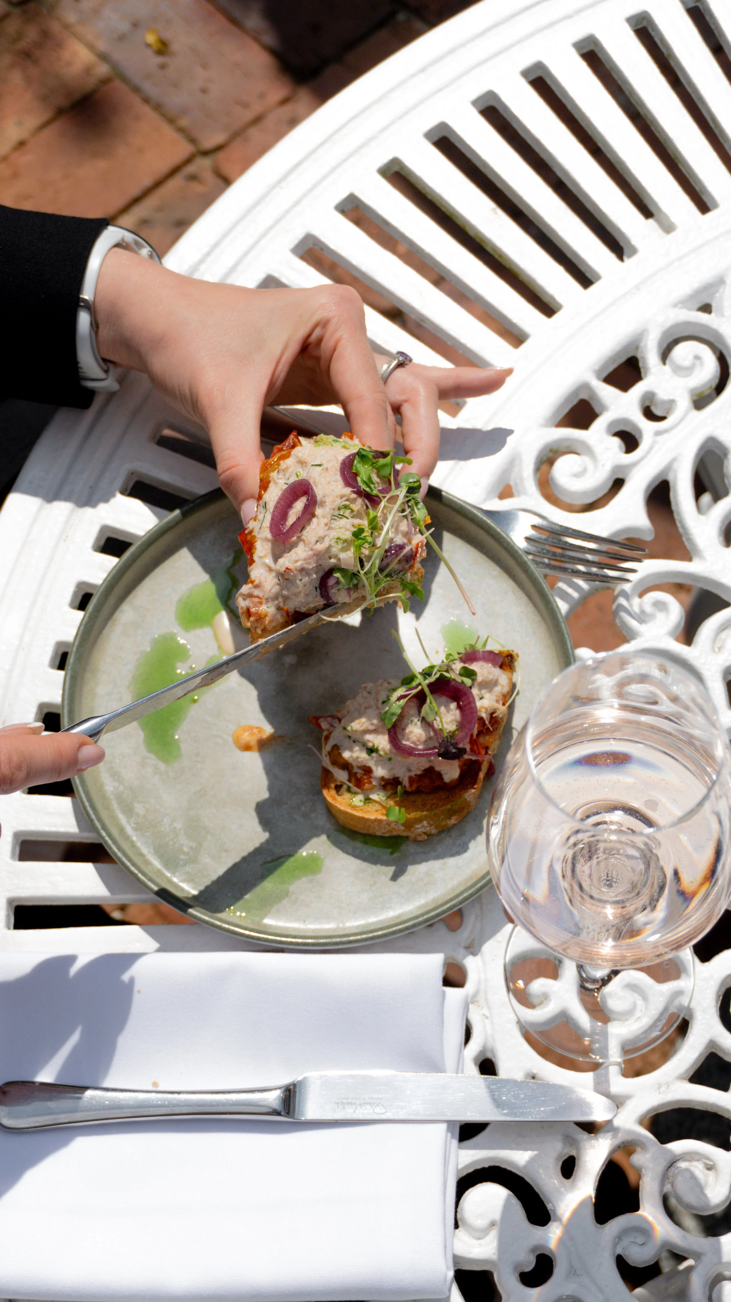 A person is holding a piece of open-faced sandwich with salad, red onion slices, and microgreens at Stanwell House