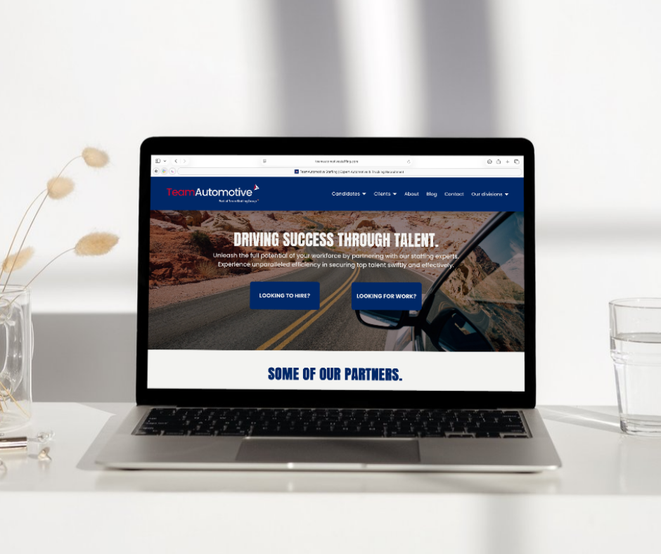 Laptop on a white desk displaying a website for Team Automotive with a slogan about driving success through talent.