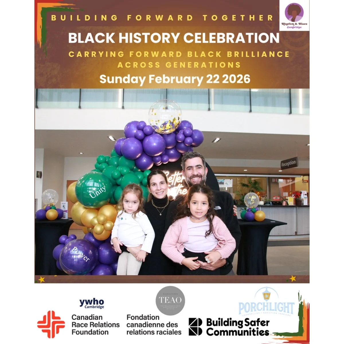 A family of four smiling at a black table with colorful balloons and a backdrop celebrating Black History. The backdrop features event details: 'Building Forward Together, Black History Celebration, Carrying Forward Black Brilliance Across Generation