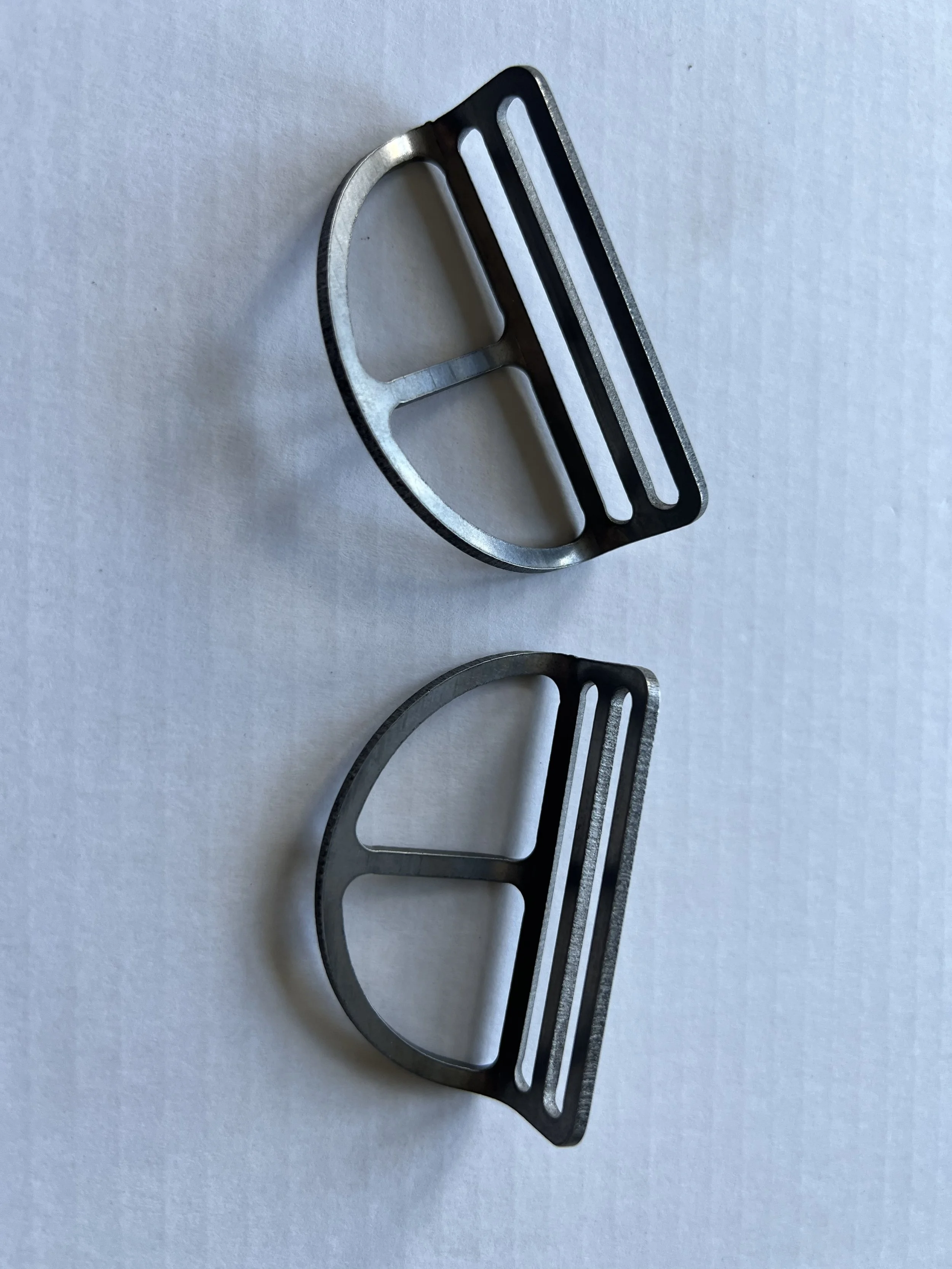 Two metal bicycle bottle cage mounts on a white surface, one above the other.