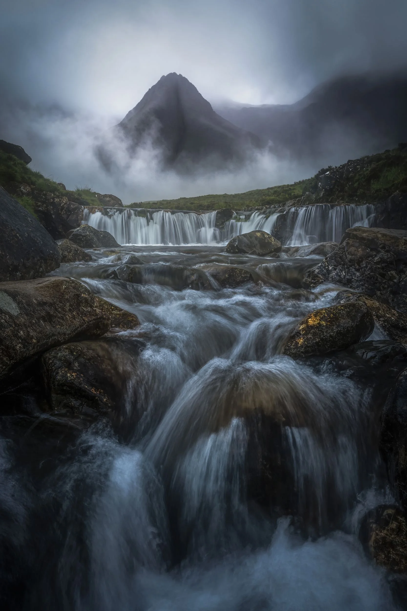 Ein stürzender Wasserfall vor einer nebligen, bergigen Landschaft