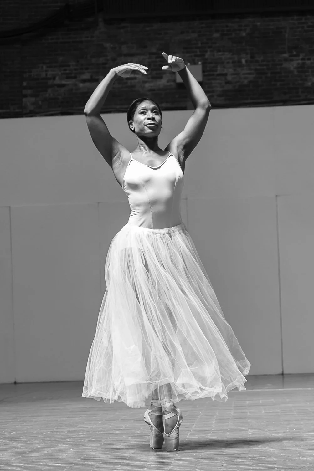 A dancer stands proudly en pointe, her skirt swirling around her ankles as she finishes her turn.