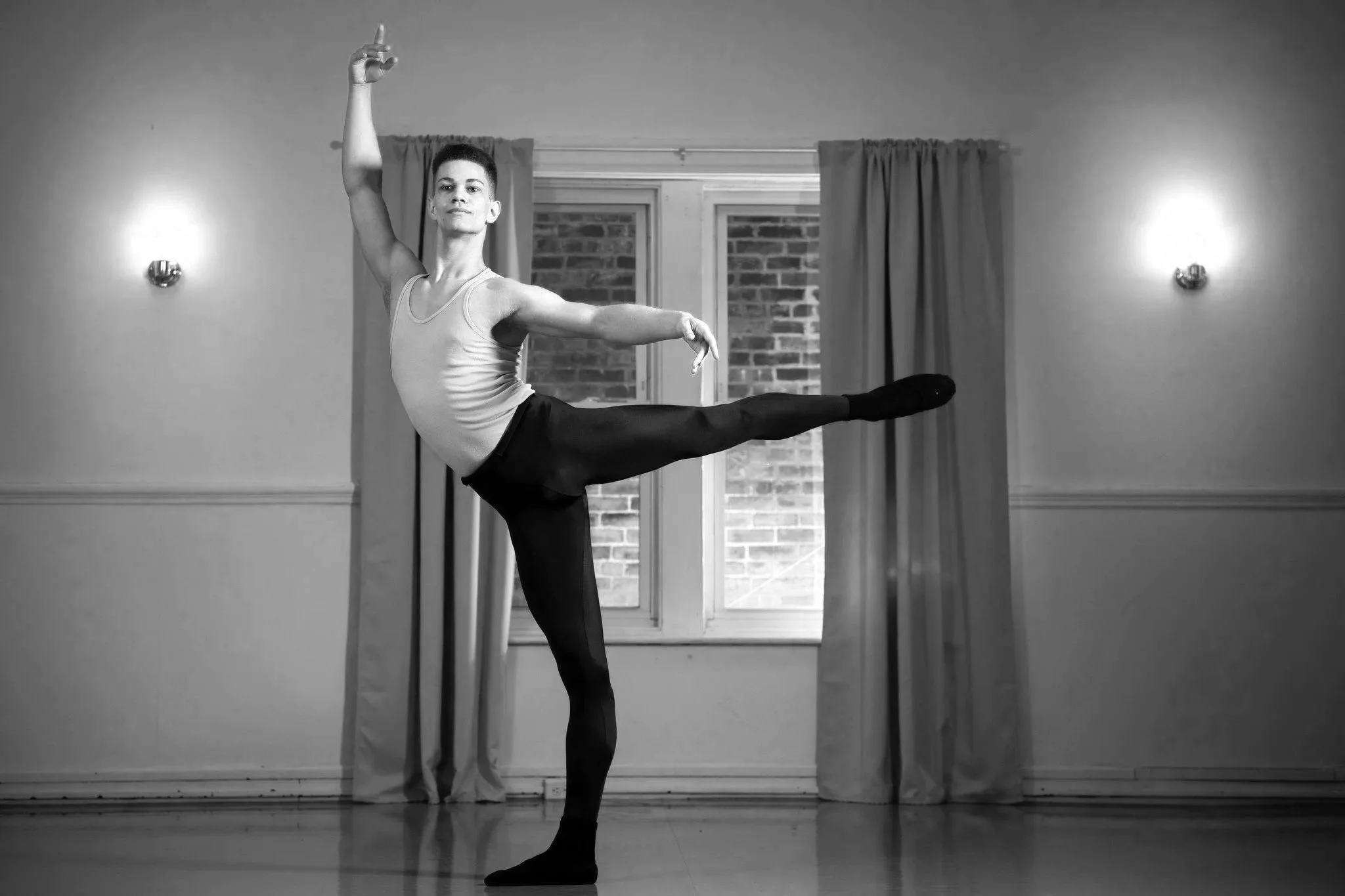 A dancer in a flawless arabesque poses in the studio.