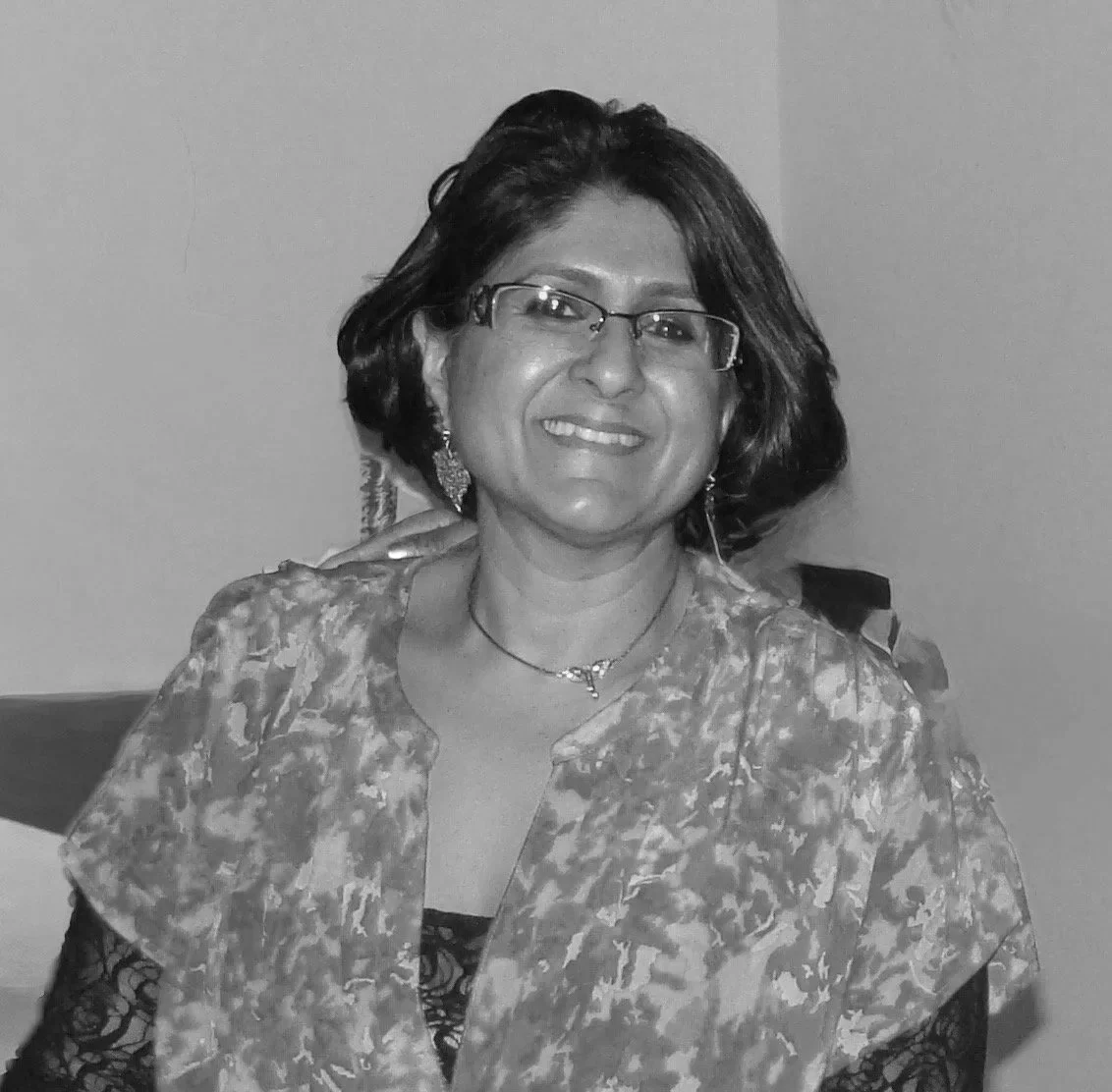 A woman with a great haircut and glasses smiles widely at the camera.