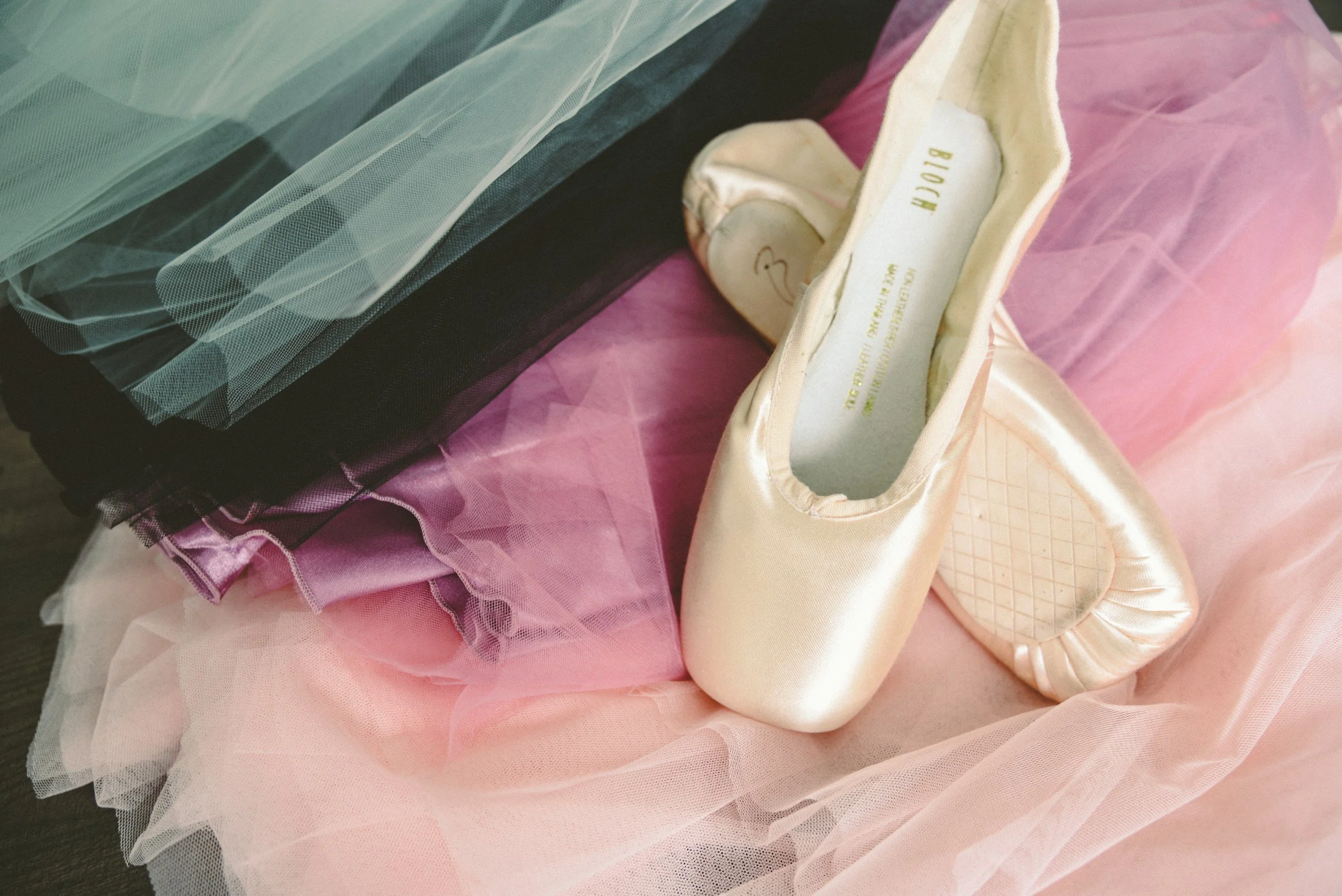 Bloch pointe shoes lie on pink and green tulle.