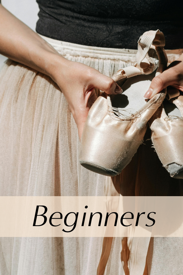 Ballet shoes held in front of a dancer's skirt.