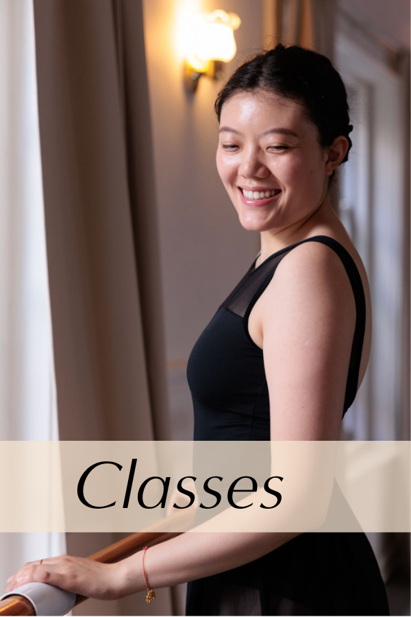 A smiling dancer stands at the barre in the studios.