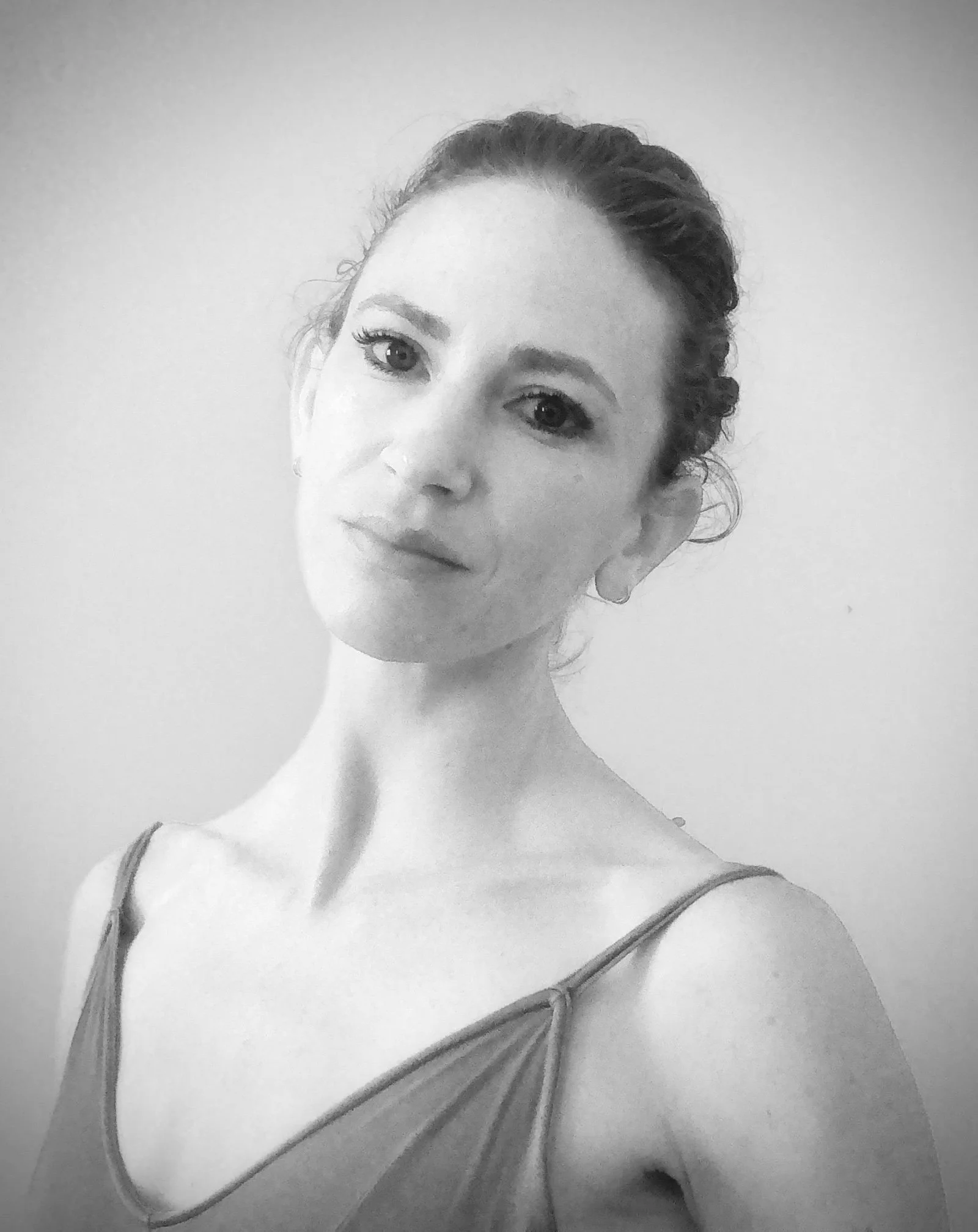 A dancer tilts her head away fro the camera, hair pulled back.