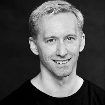 Patrick smiliest the camera in an official headshot.