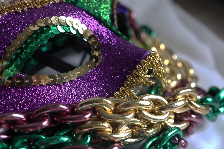 Close up photograph of a purple and gold Mardi Gras mask.