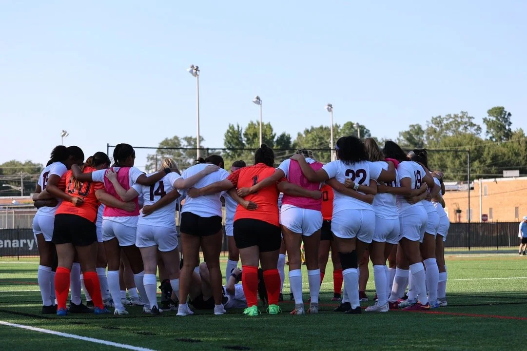 Photograph of Centenary Ladies' Soccer team in a pre-game huddle.