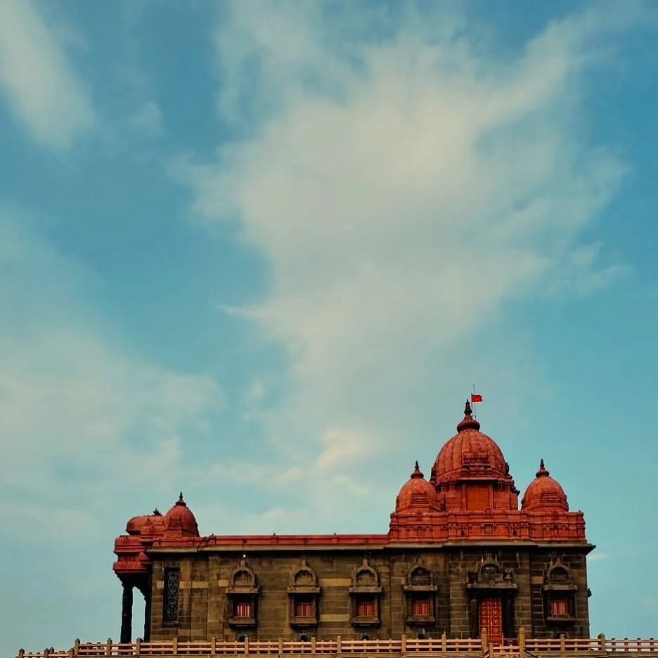 ..::V R M::..
.
. 
Beneath the blue and endless sky,
The temple stands with spires high.
Its red crown shines, its walls so old,
A timeless tale of faith untold.

The flag waves gently in the breeze,
A haven of calm, a place of peace.
Where earth and