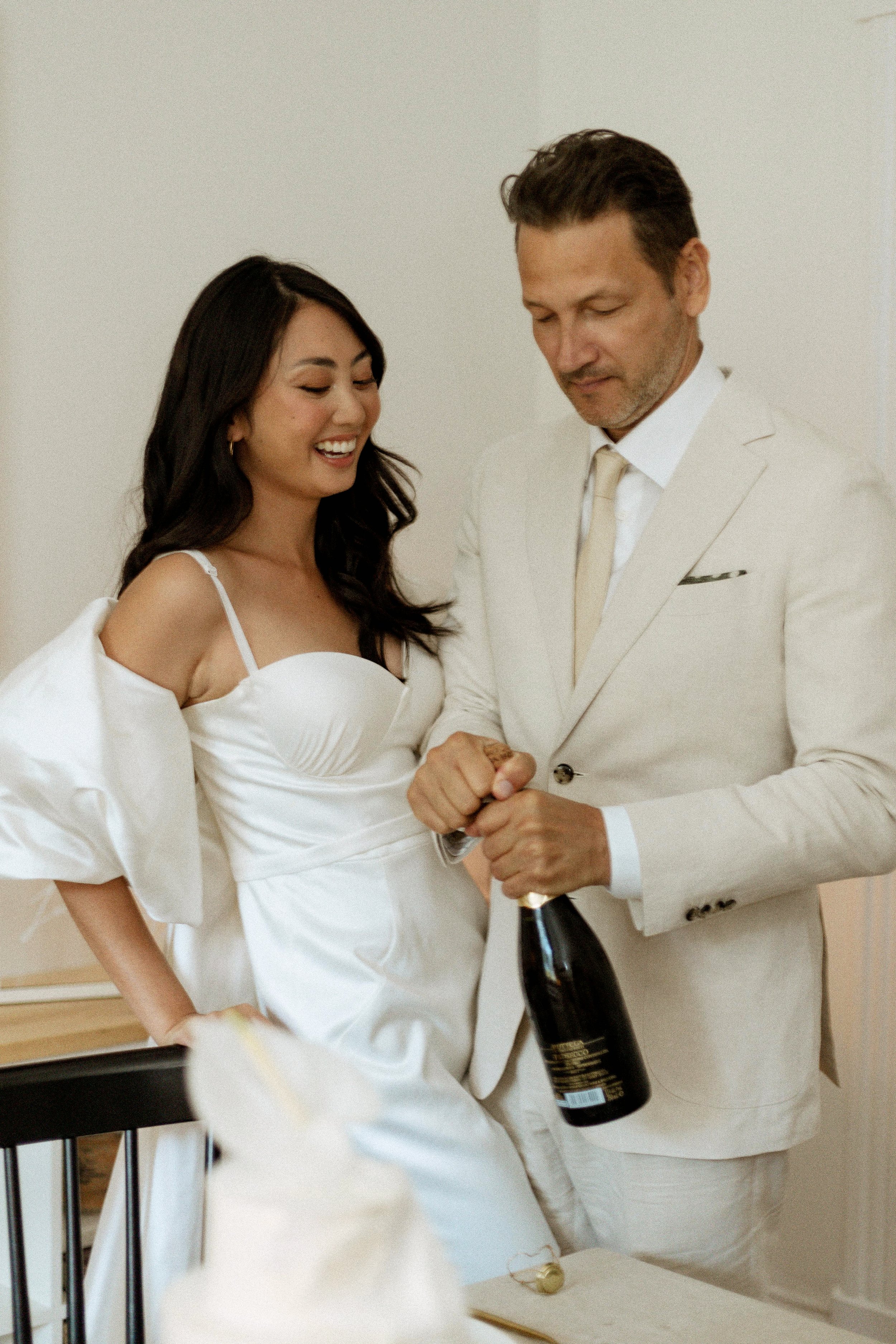 bride and groom opening up bottle of champagne during their elopement