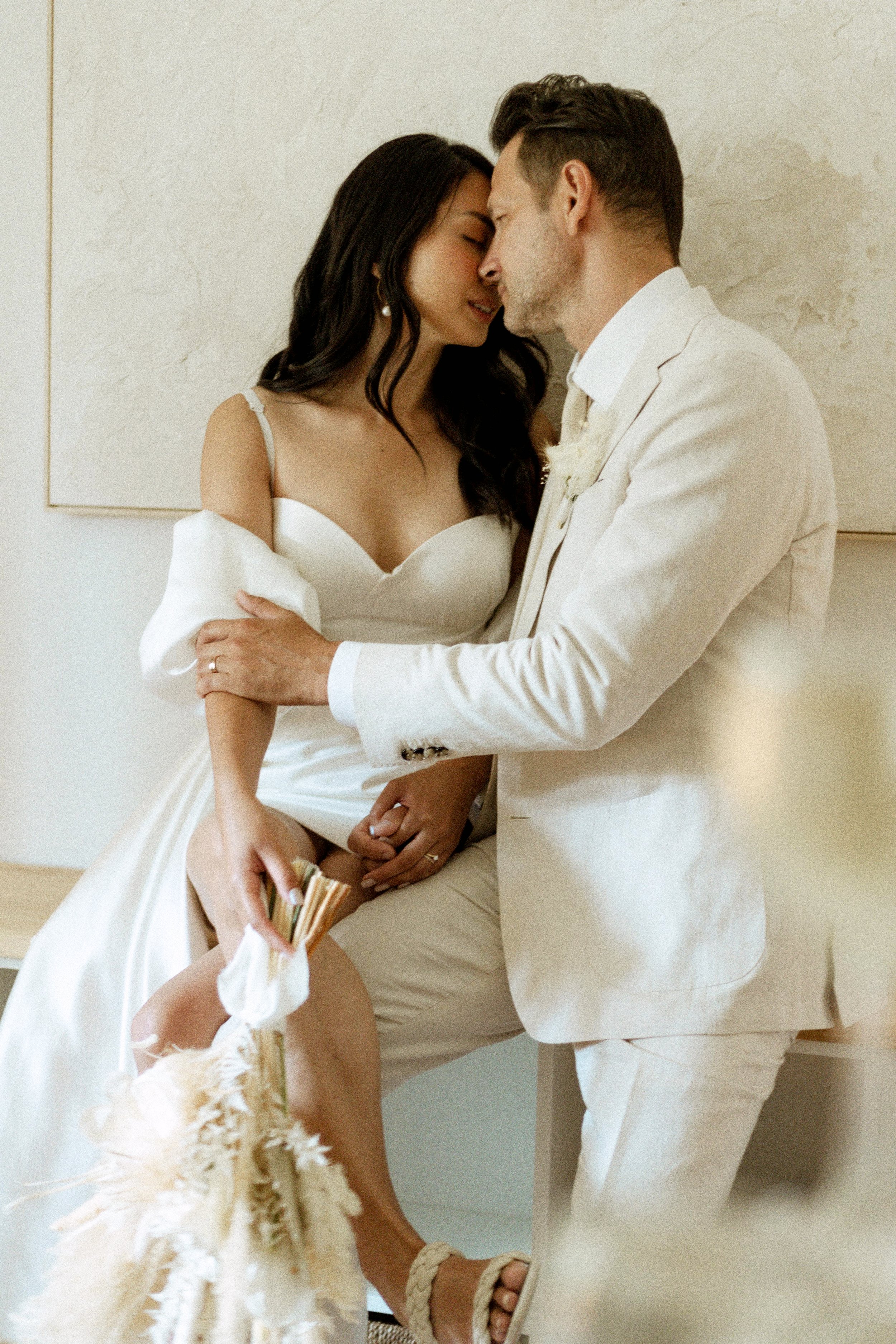 photo of bride and groom kissing while sitting on credenza while celebrating their elopement together - wedding photographer in Toronto
