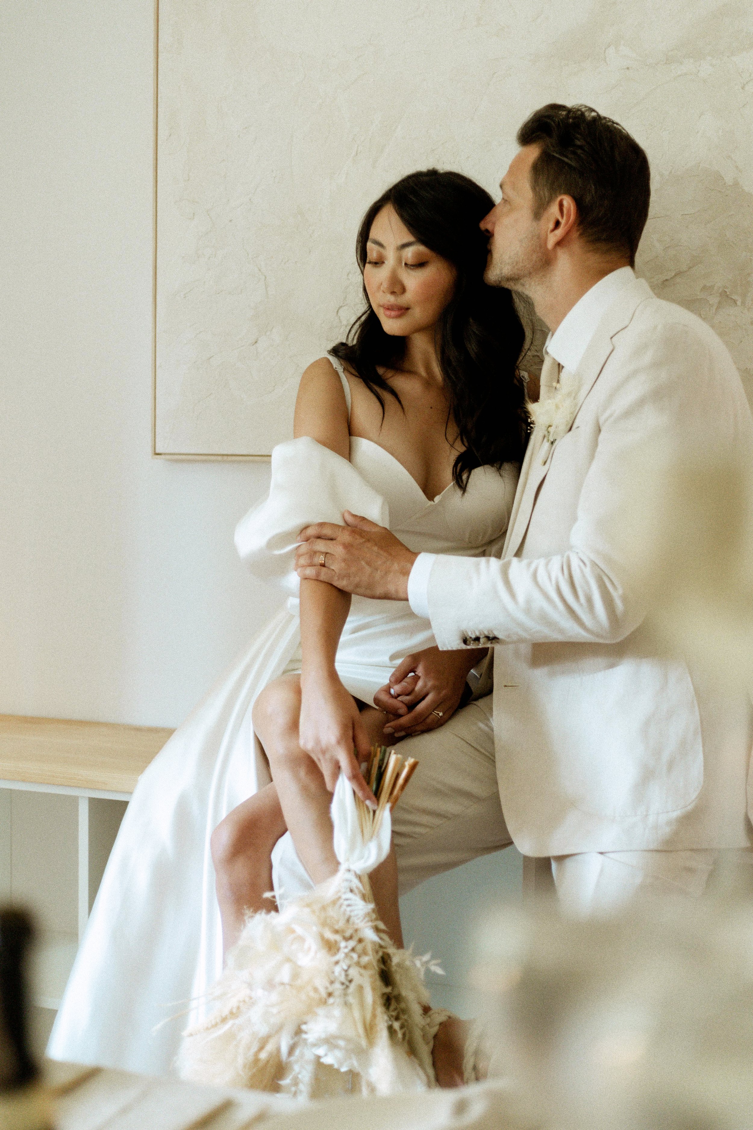 photo of bride and groom kissing while sitting on credenza while celebrating their elopement together - wedding photographer in Toronto
