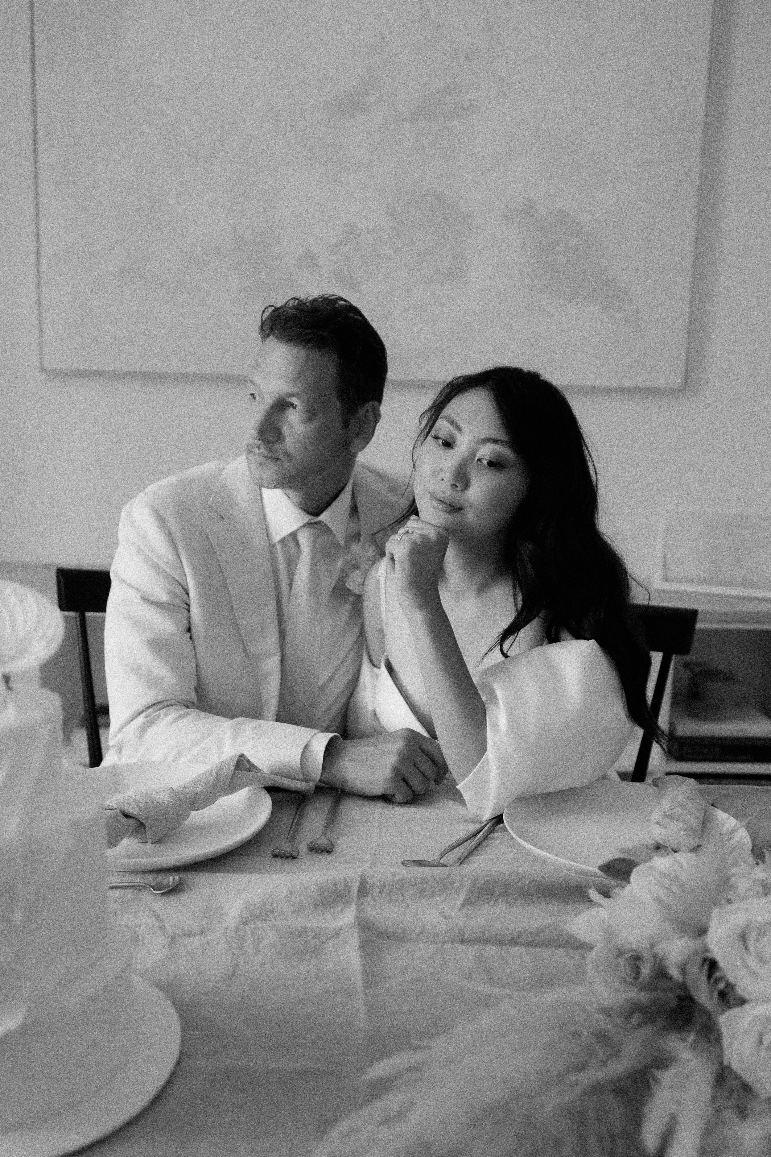 bride and groom sitting next each other and posing for camera - black and white wedding photography