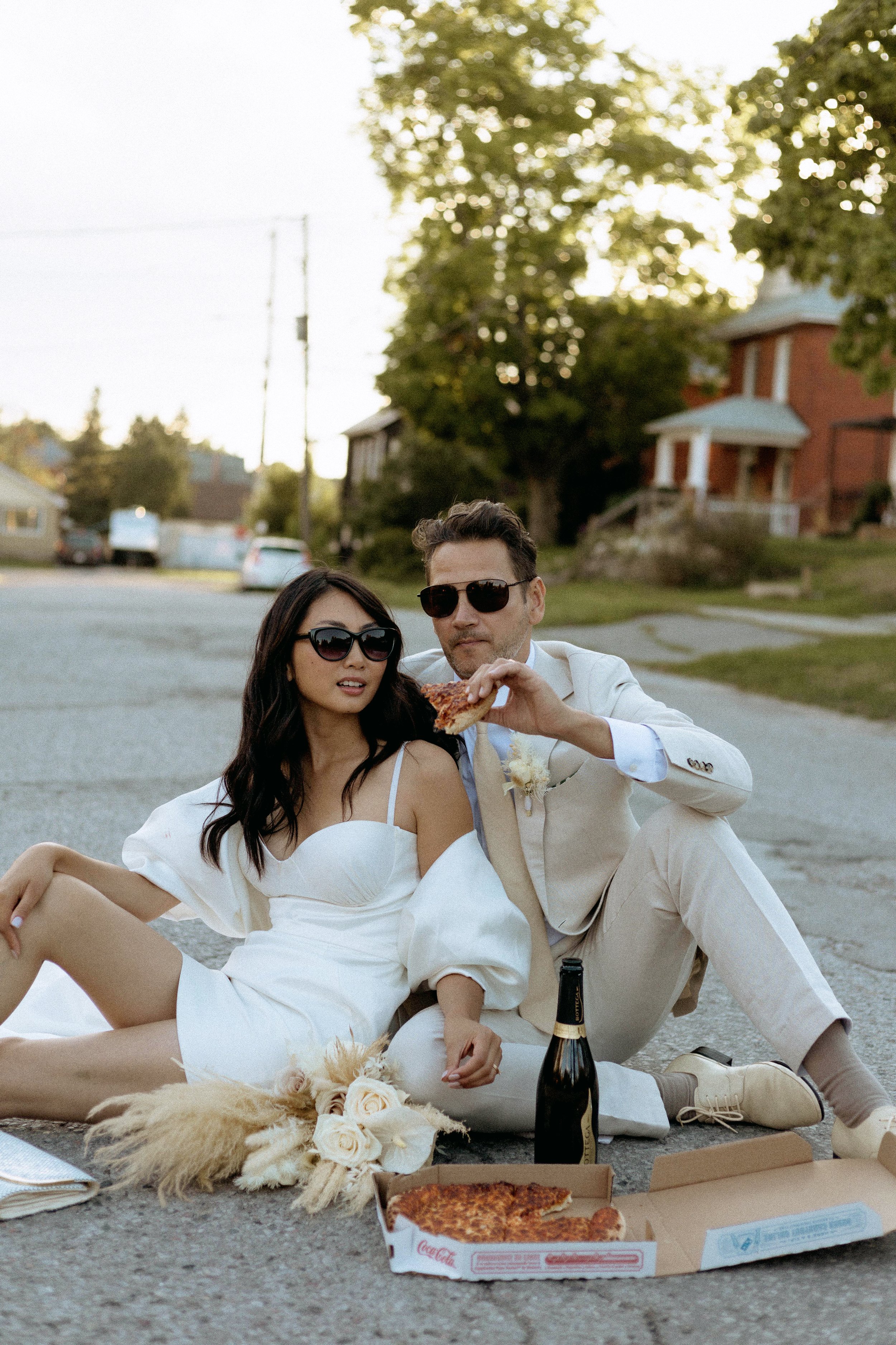 bride and groom walking down the road to continue celebrating their elopement in toronto while eating pizza on the road