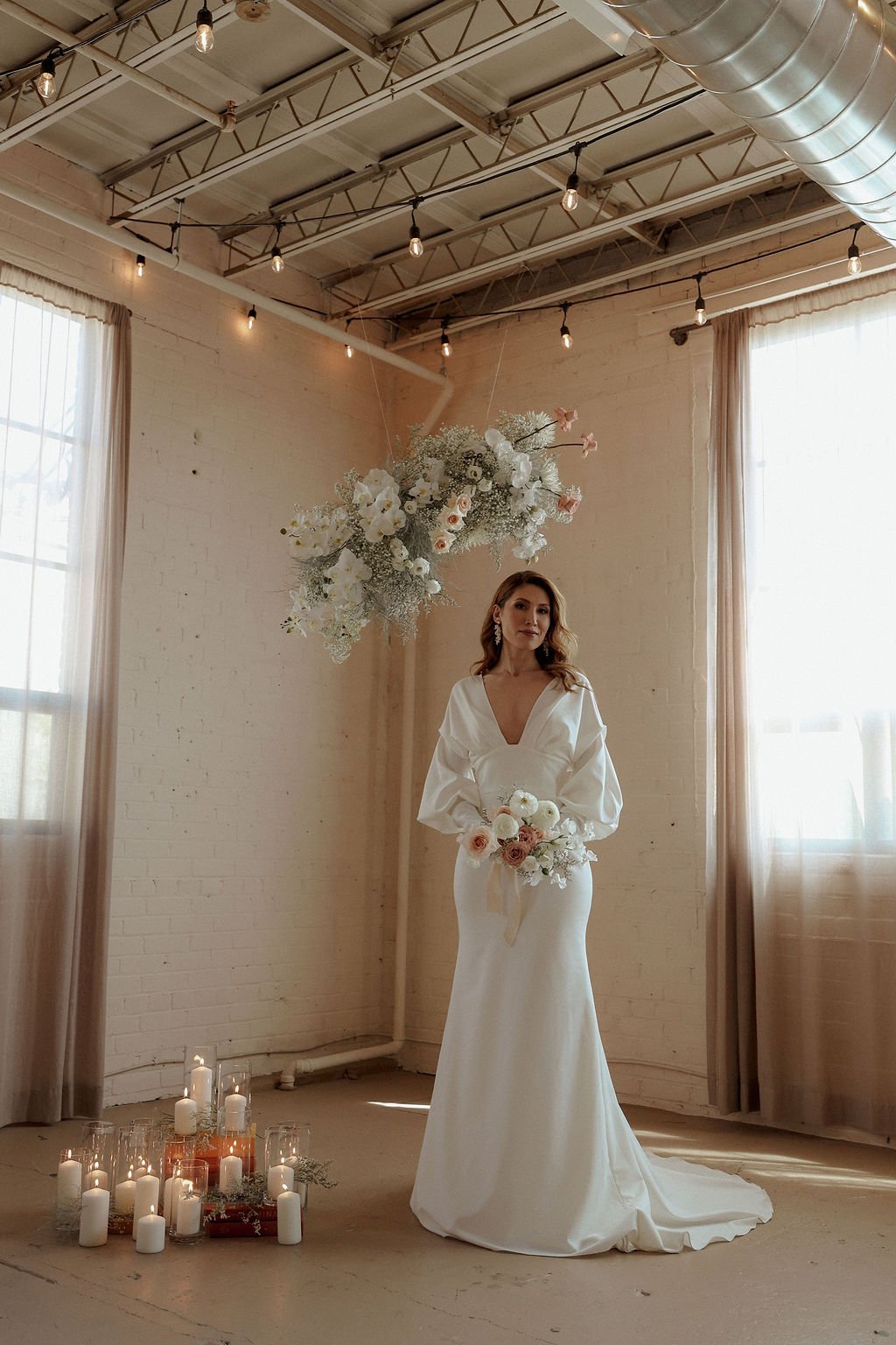 bride holding flowers while under a flower arch
