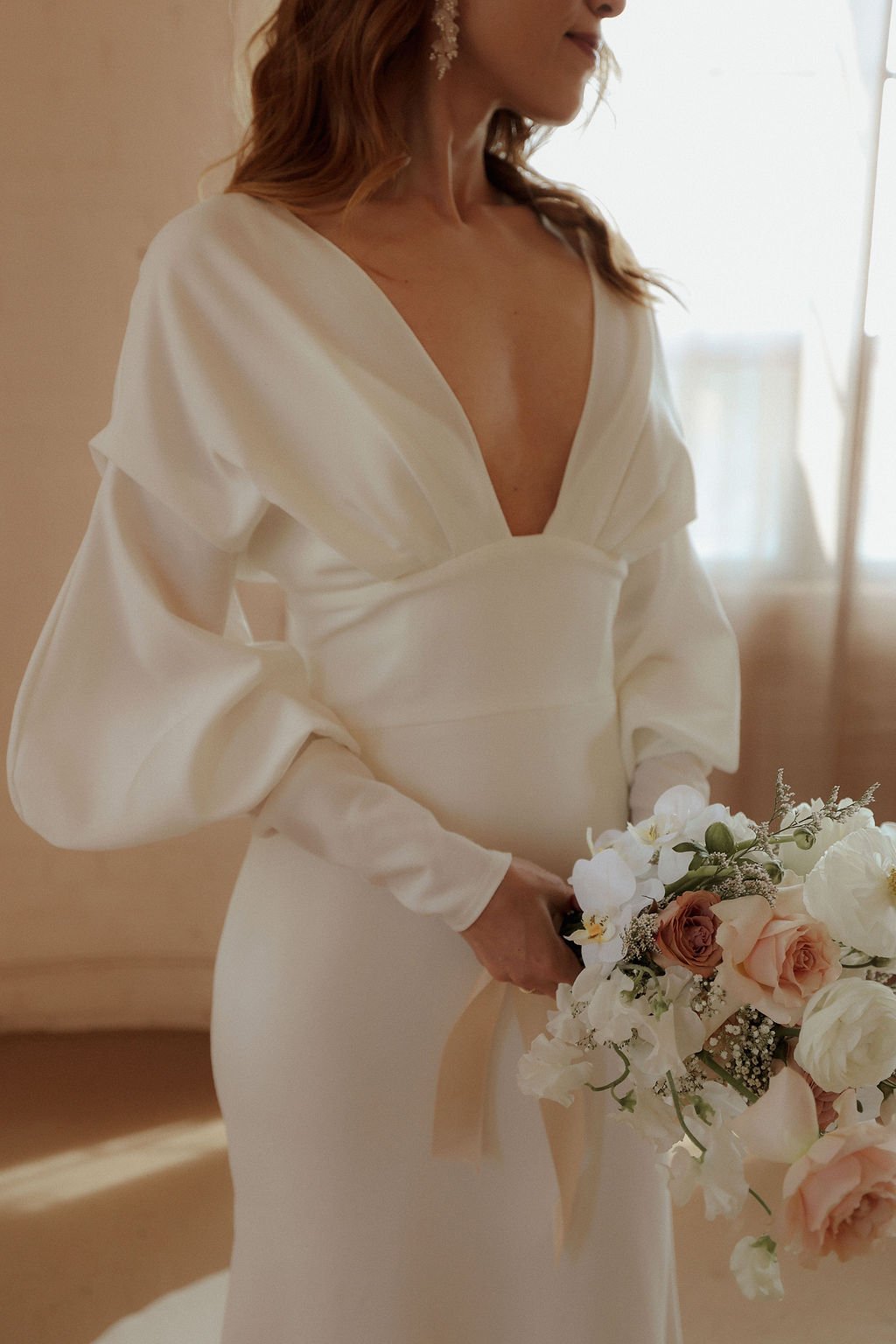 bride holding flowers and posing in modern and sleek wedding dress