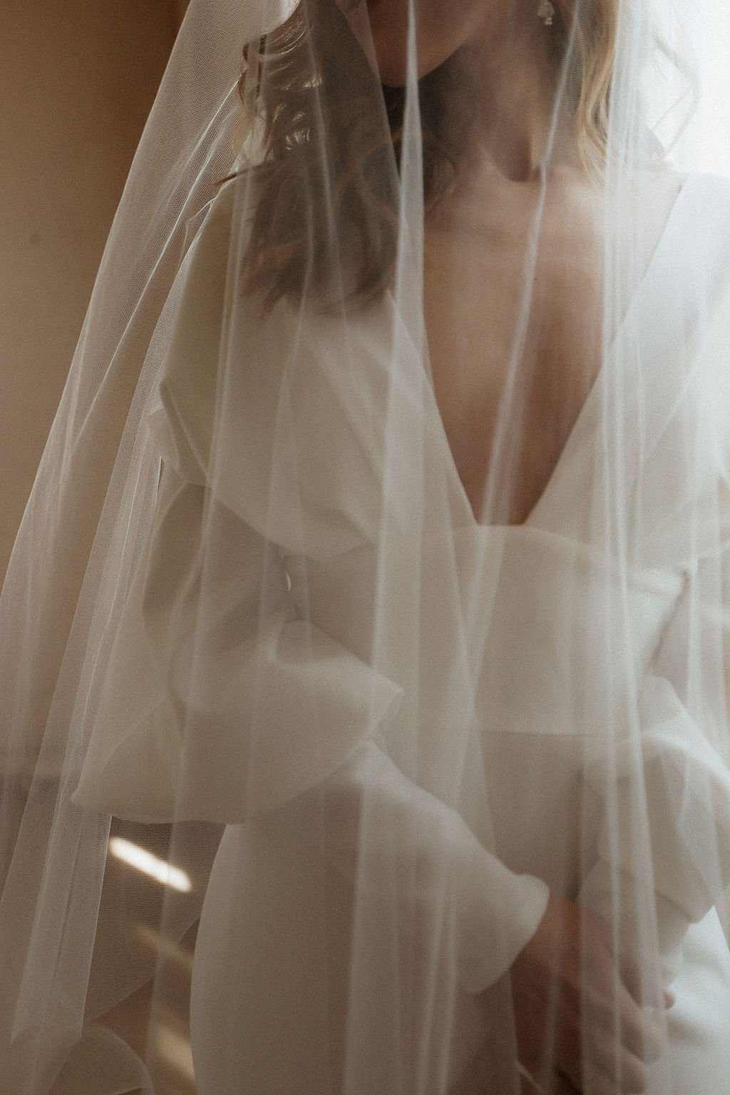 bride standing near window with viel 