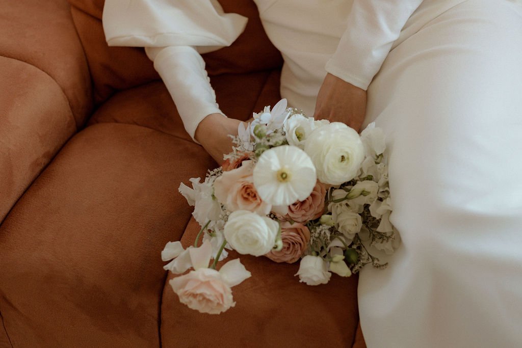 bride laying on couch while holding onto her flower bouquet for her bridal portraits