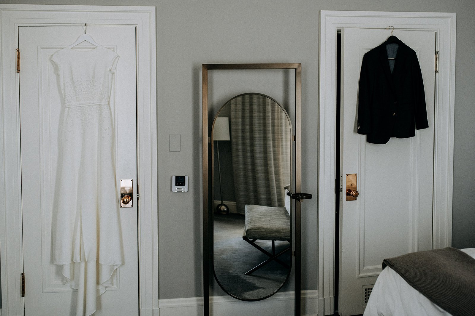  wedding dress and suit jacket hanging in front of closet with mirror 
