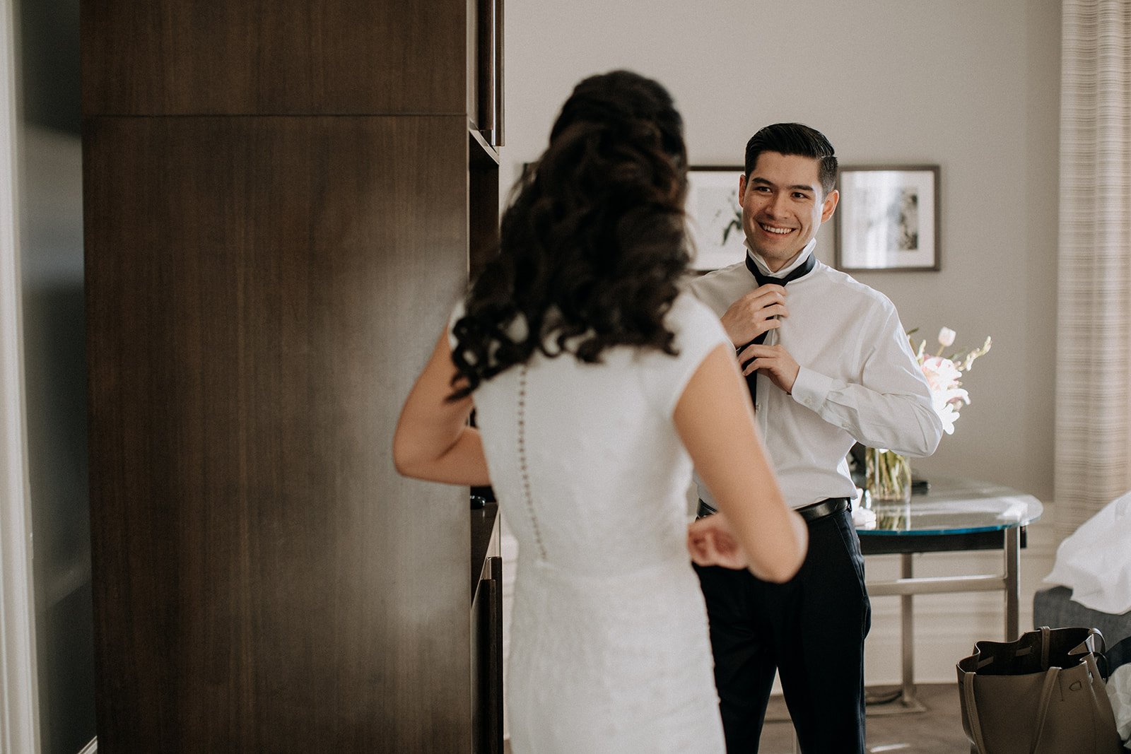  bride and groom looking at each other while they get ready 