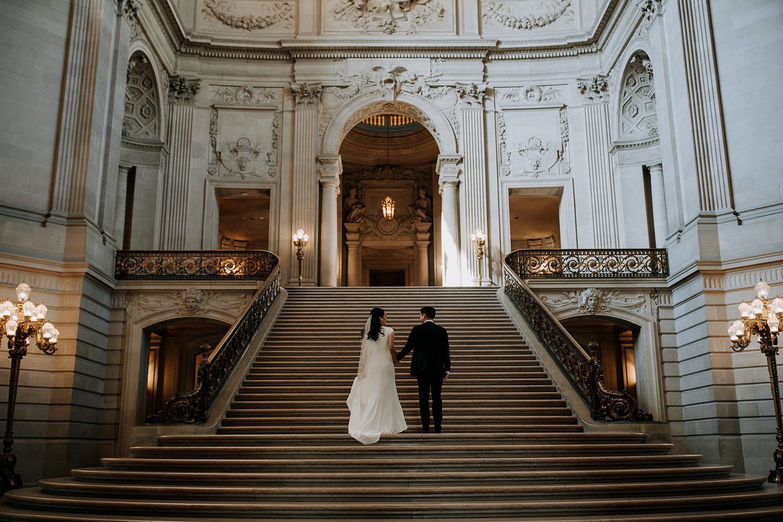  bride and groom walking up grand staircase of city hall 