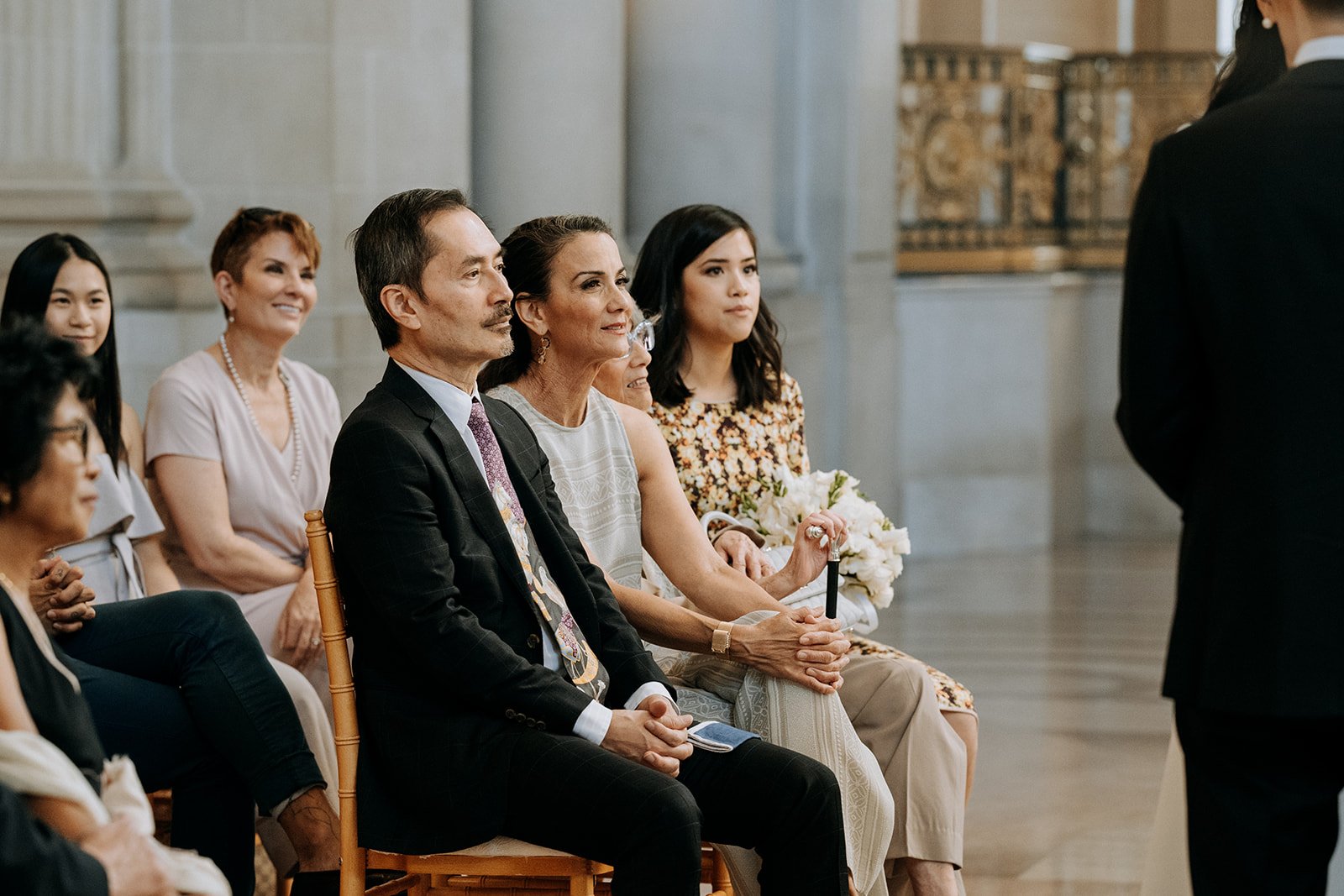  wedding guests smiling while watching ceremony  