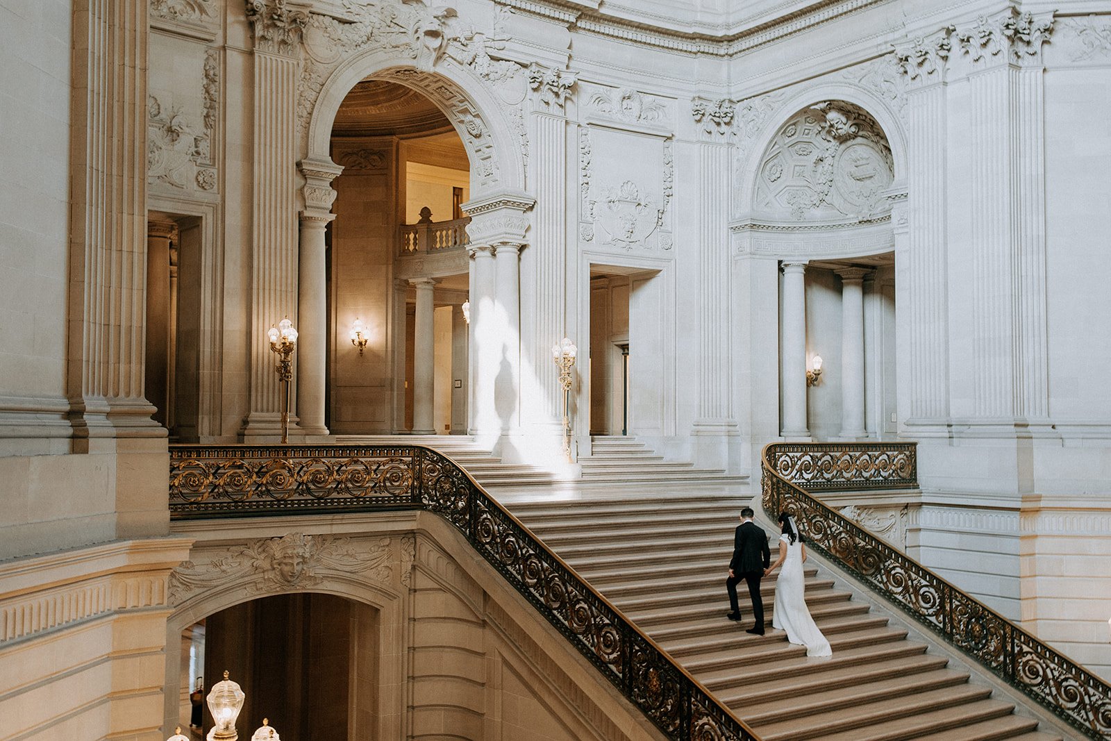  bride and groom walking up grand staircase at city hall  