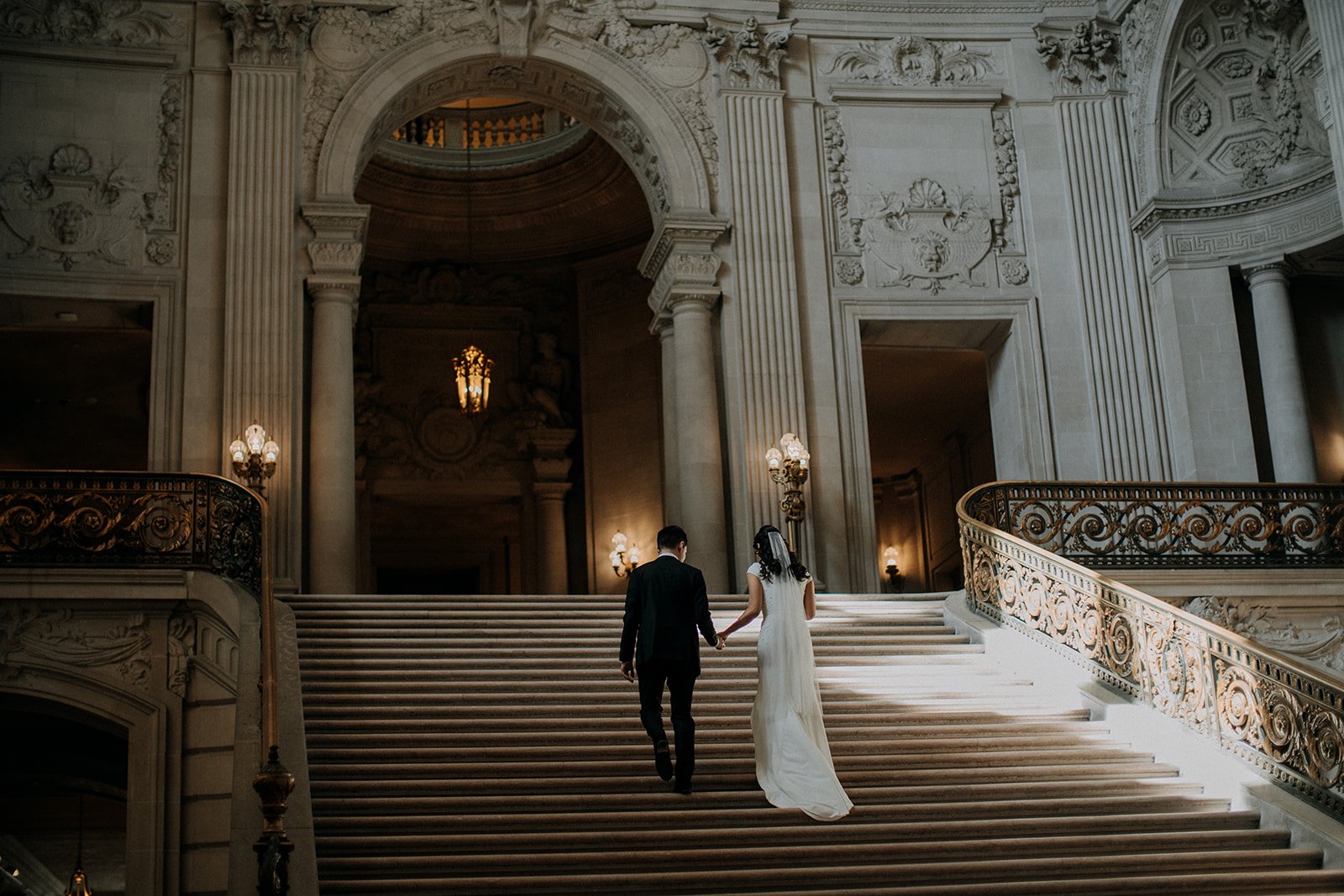  bride and groom walking up grand staircase at city hall 