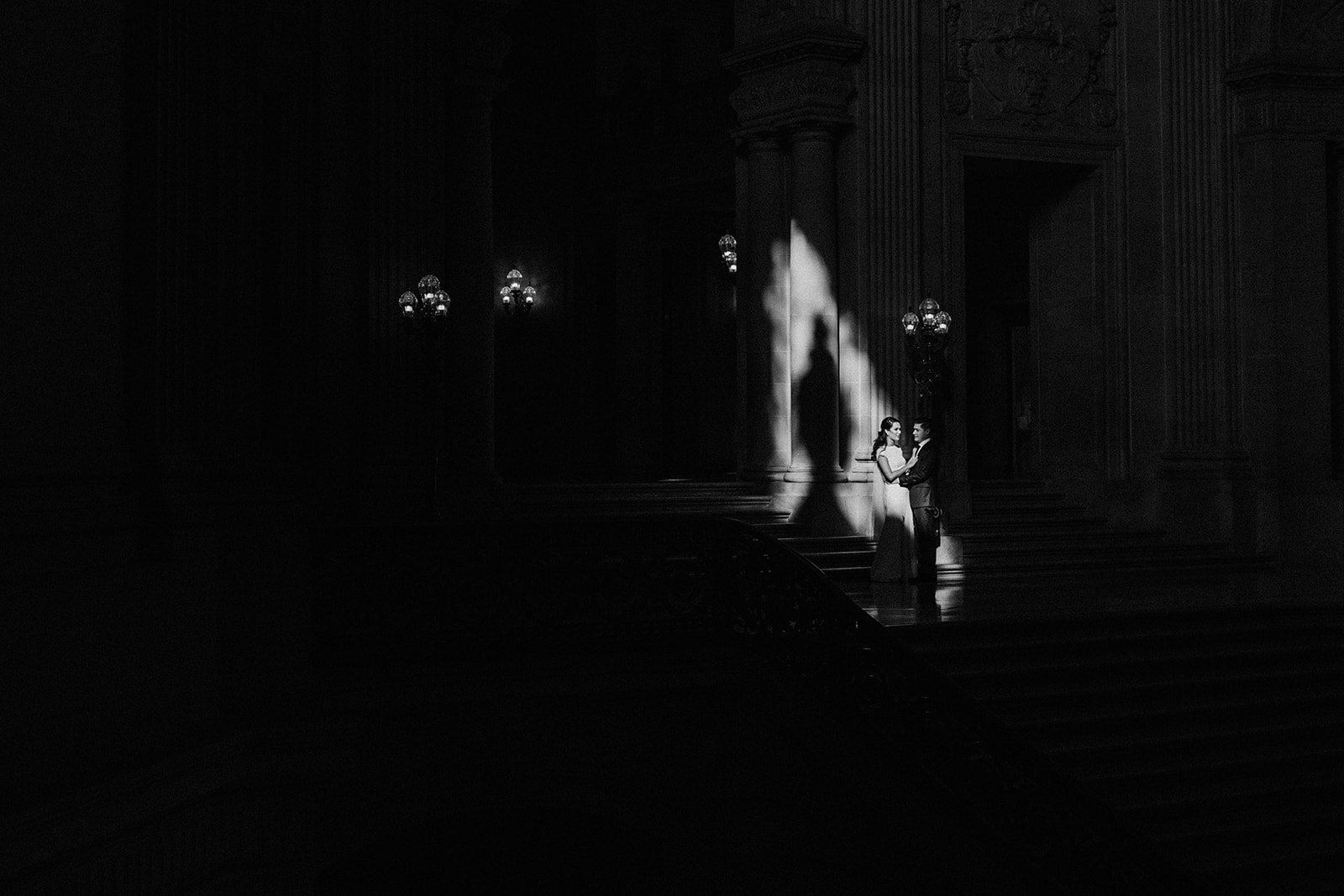  bride and groom standing in sunlight casting a shadow on city hall staircase  